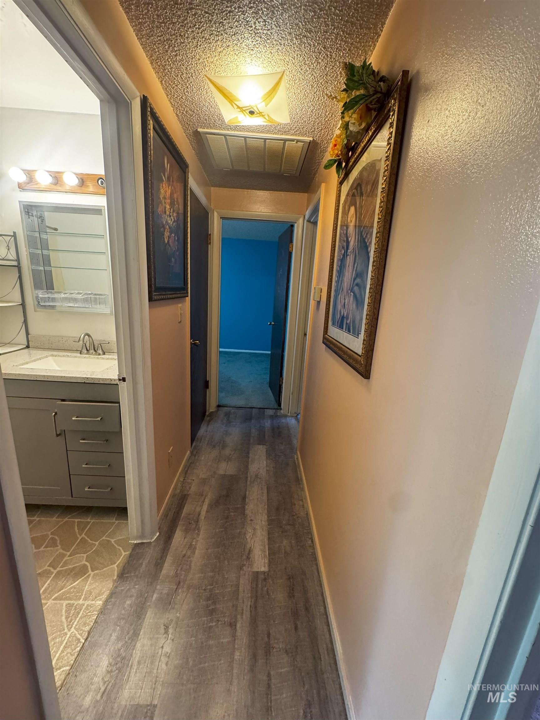 Corridor with dark wood-style floors and a textured ceiling