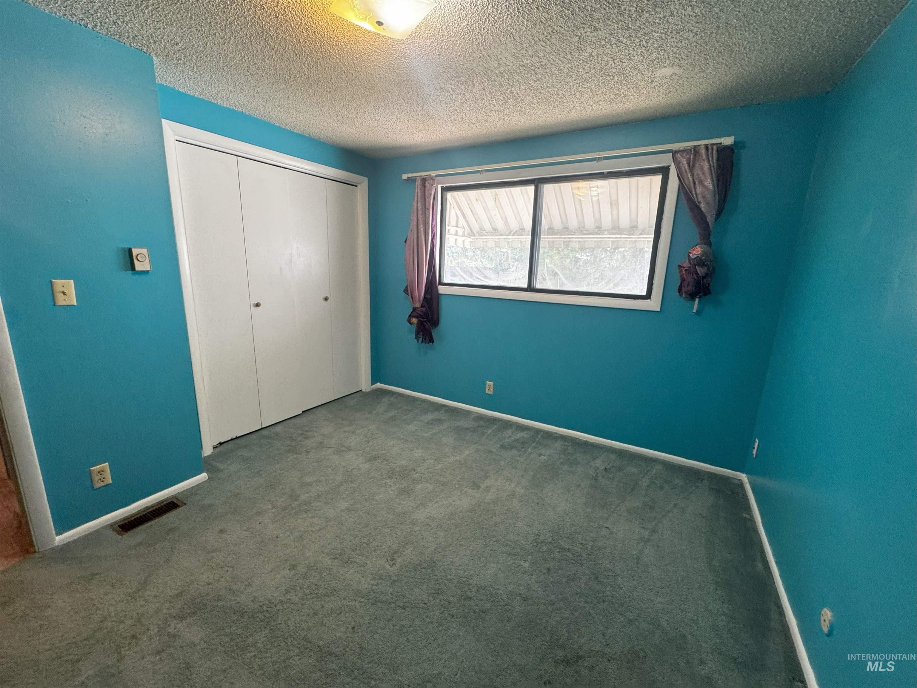 Unfurnished bedroom with a closet, carpet floors, and a textured ceiling