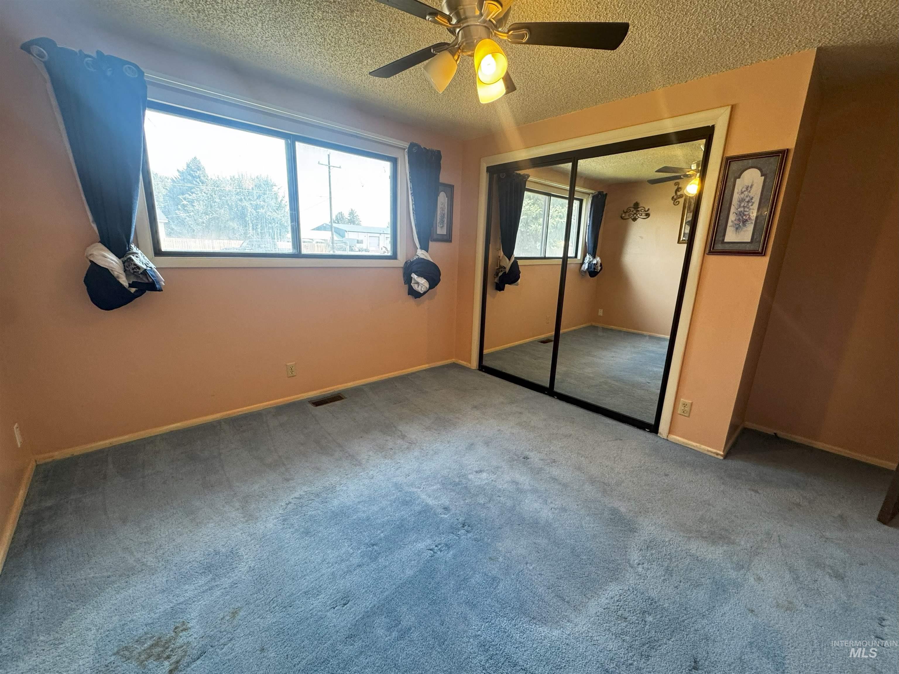Unfurnished bedroom featuring a textured ceiling, a ceiling fan, carpet flooring, and a closet
