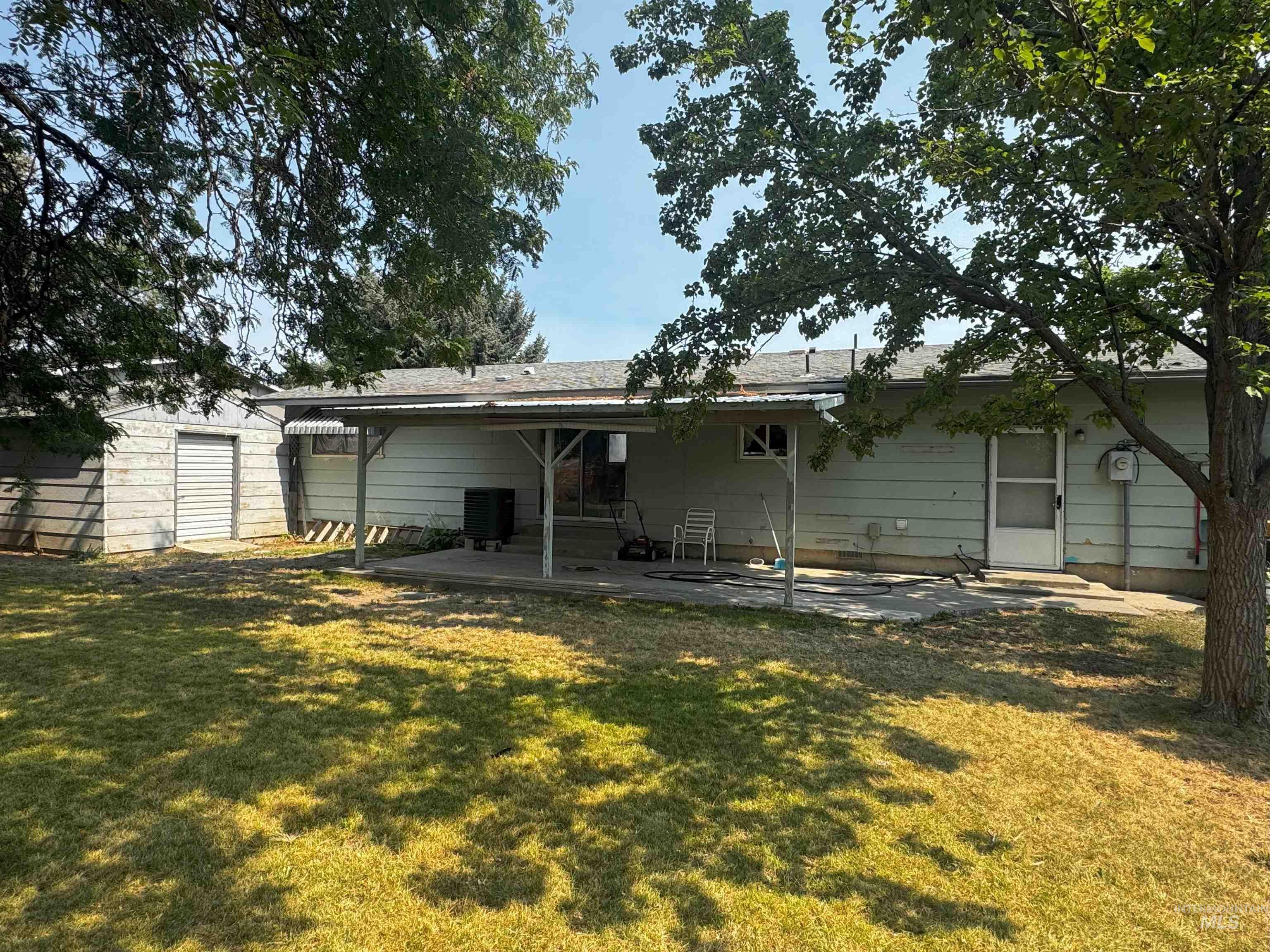 Back of house with a patio area, a yard, and an outbuilding