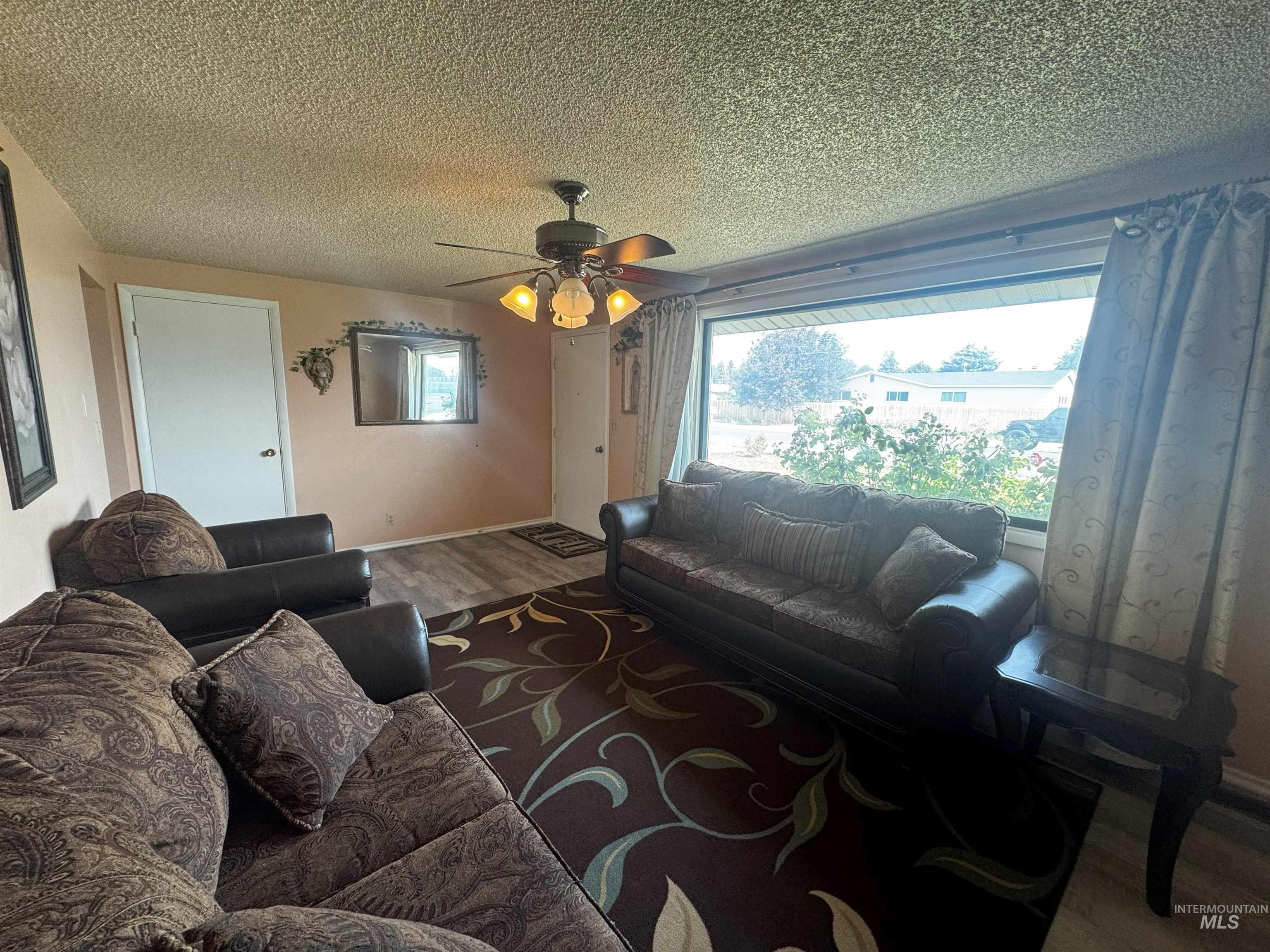 Living area featuring wood finished floors, a textured ceiling, and ceiling fan