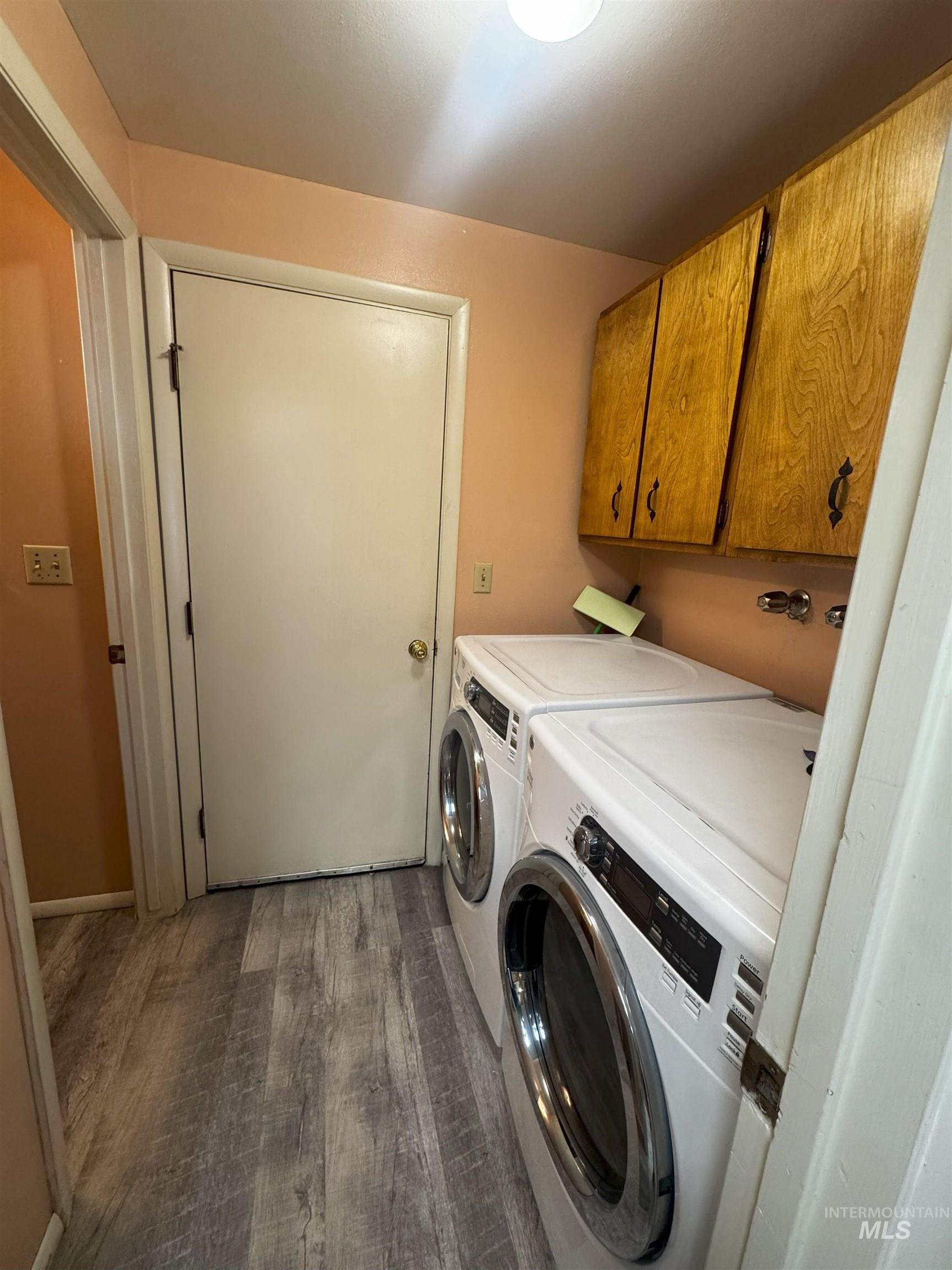 Washroom with cabinet space, dark wood finished floors, and washer and dryer