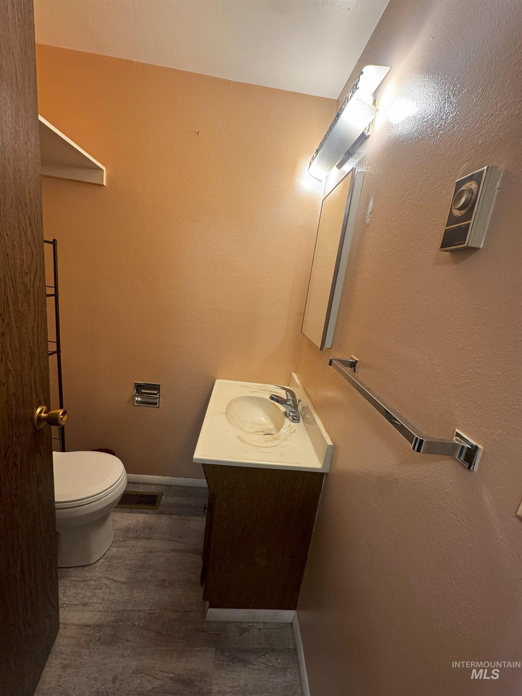 Half bathroom with vanity, dark wood finished floors, and a textured wall