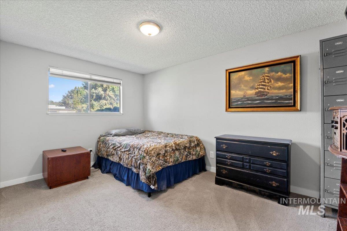 Carpeted bedroom featuring a textured ceiling and baseboards