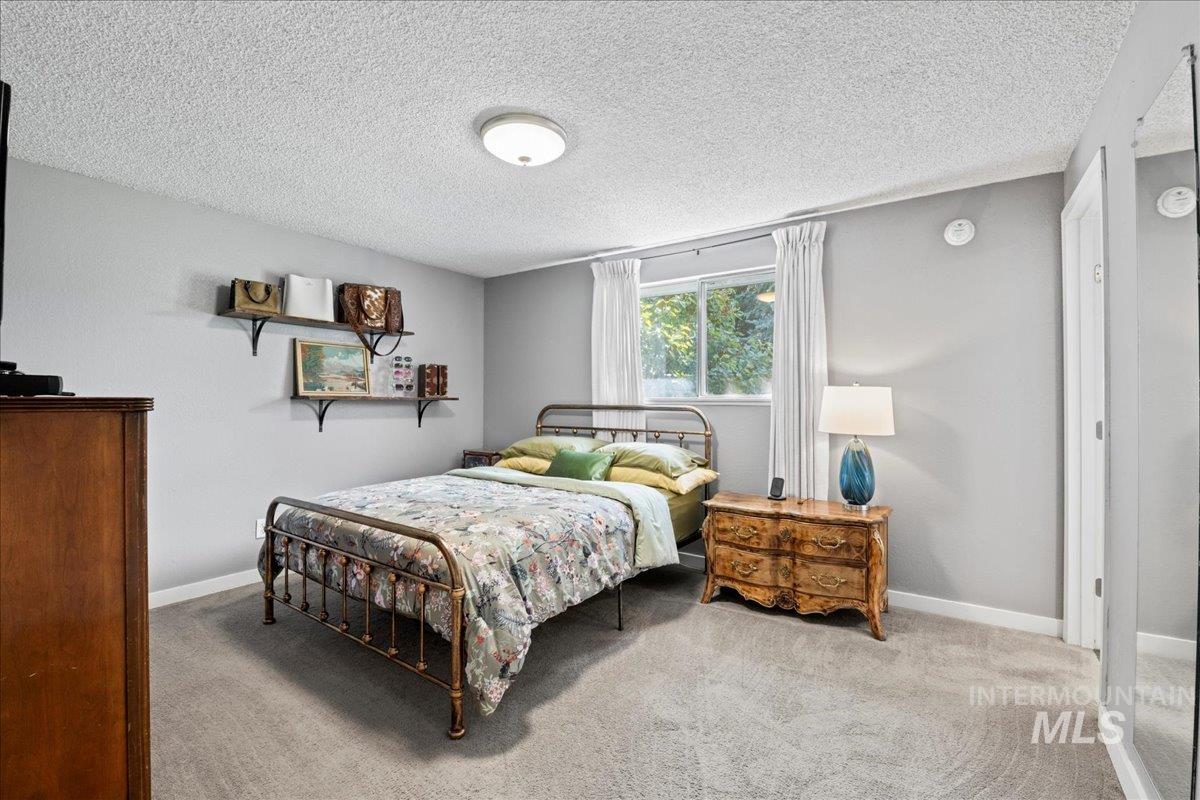 Carpeted bedroom with a textured ceiling and baseboards