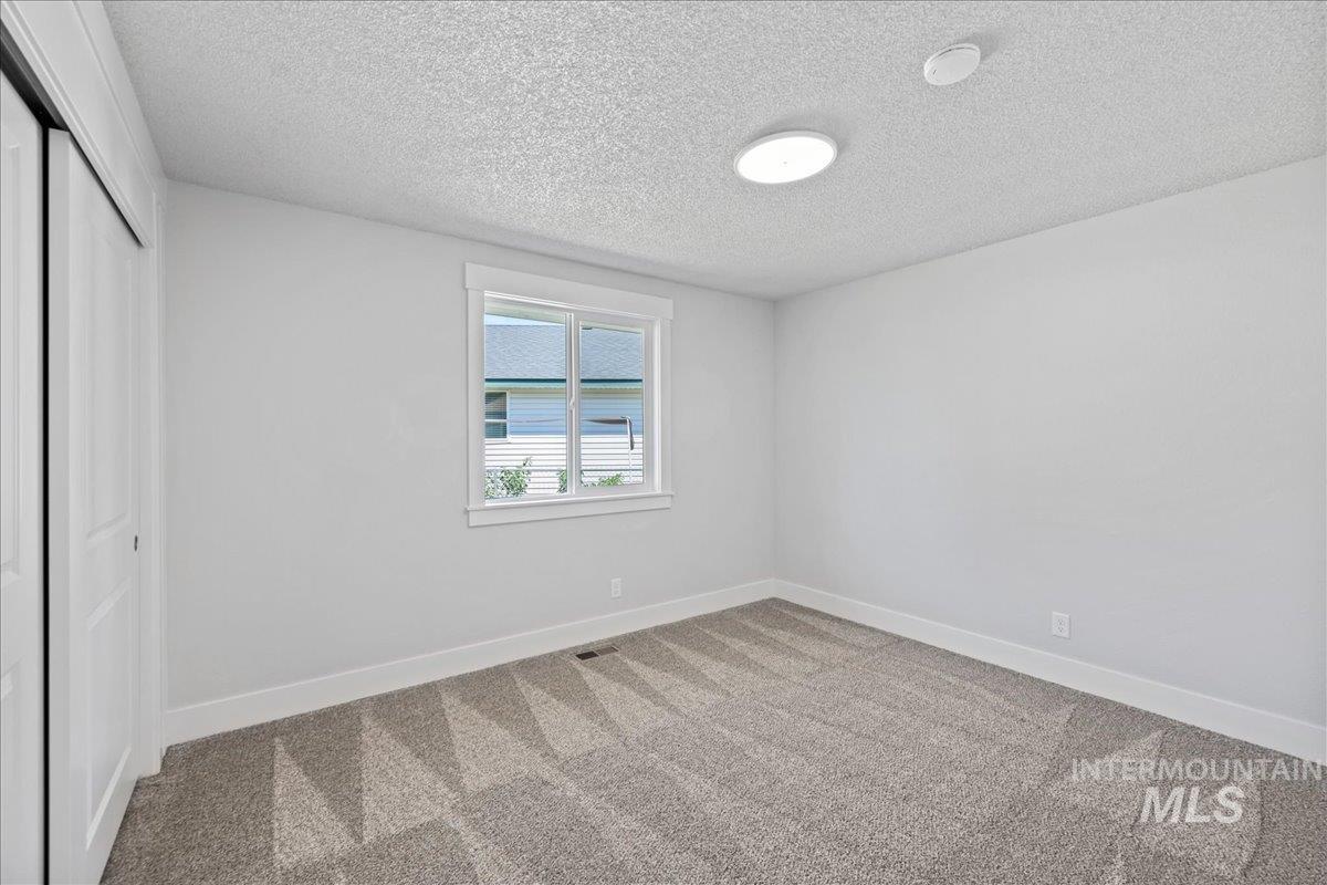 Unfurnished bedroom featuring a closet, carpet flooring, and a textured ceiling