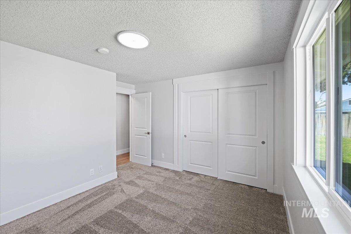 Unfurnished bedroom with a closet, carpet floors, and a textured ceiling