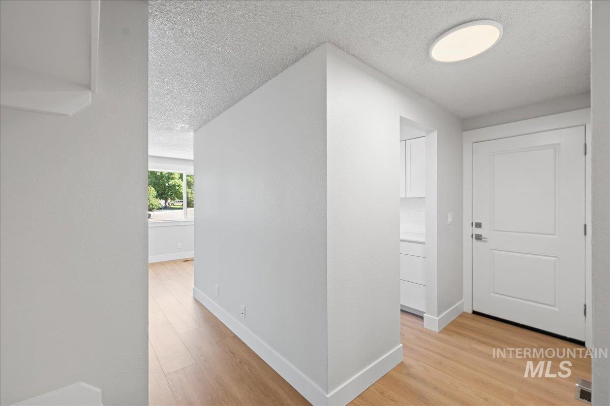 Hallway with a textured ceiling and light wood-type flooring