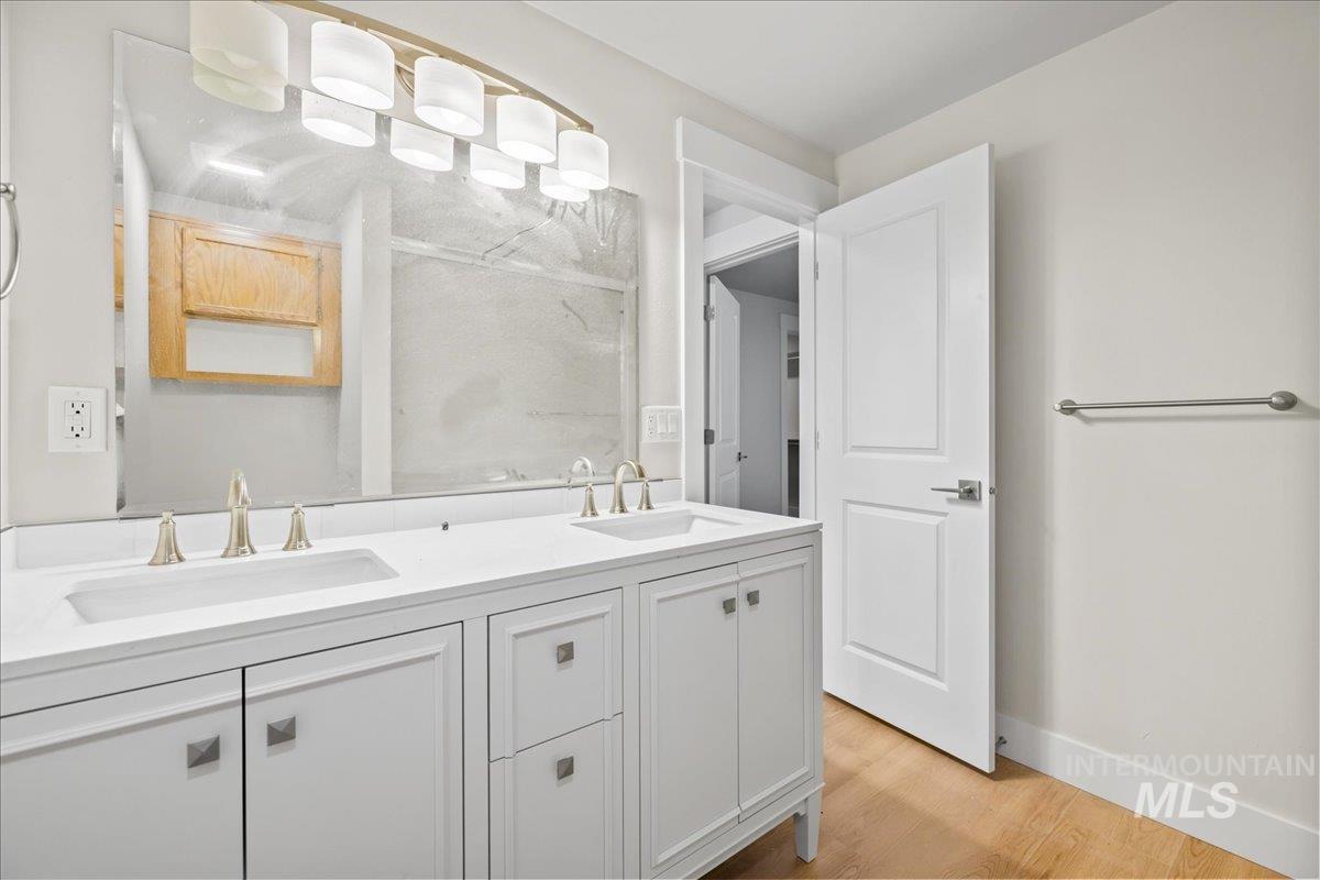 Full bath with light wood finished floors and double vanity