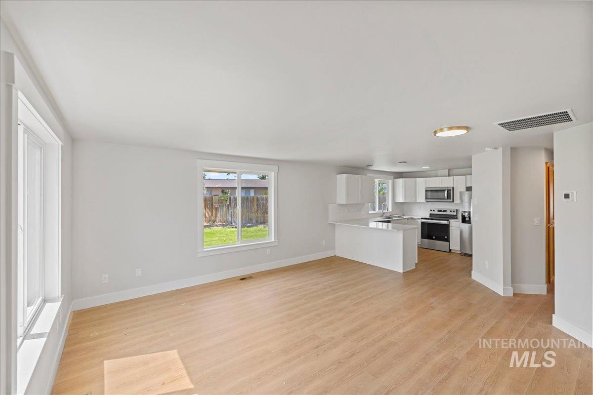 Unfurnished living room with light wood finished floors and baseboards