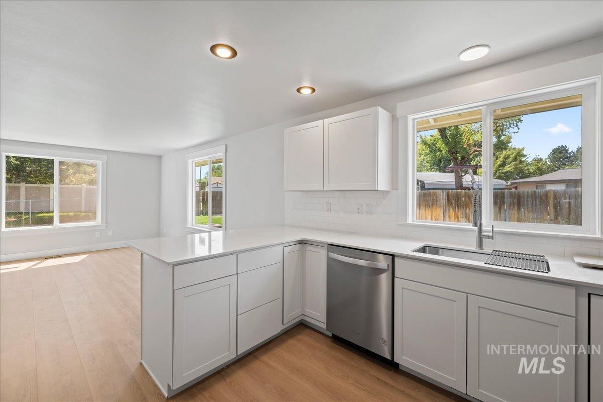 Kitchen featuring decorative backsplash, plenty of natural light, dishwasher, light wood-style floors, and recessed lighting