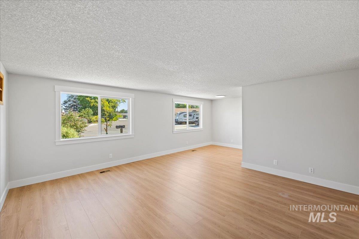 Unfurnished room featuring light wood-type flooring and a textured ceiling