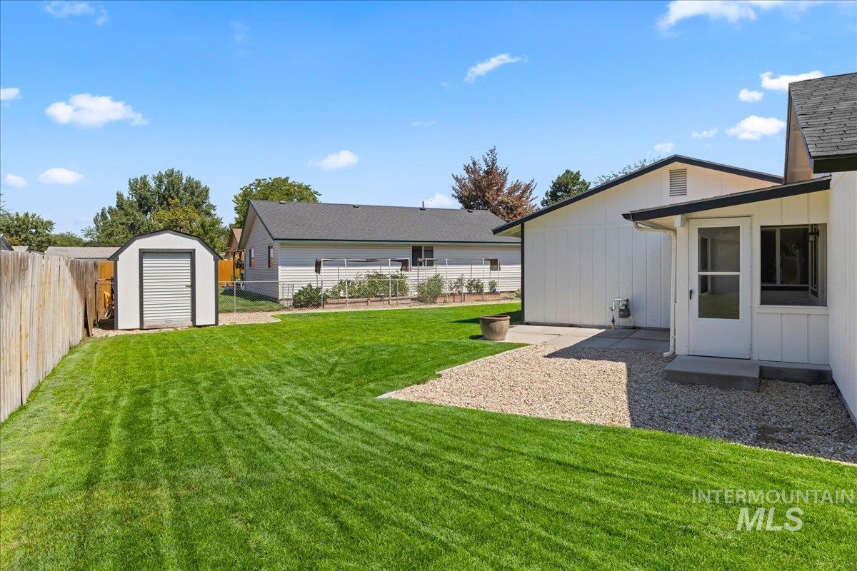 Fenced backyard featuring a shed