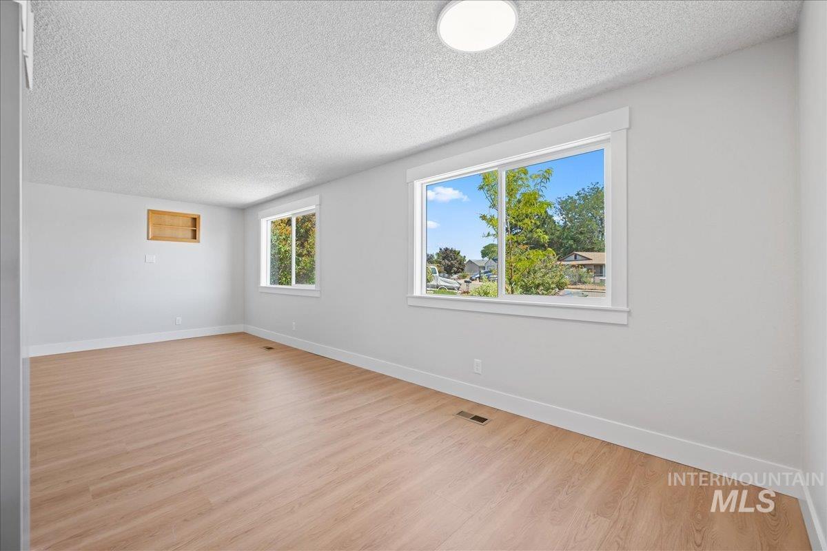 Unfurnished room featuring a textured ceiling and light wood-type flooring
