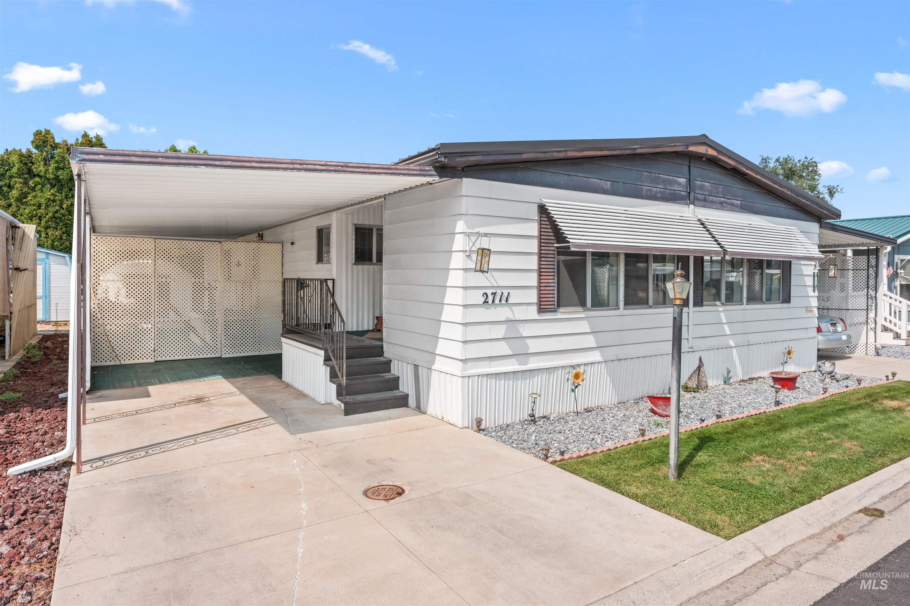 Manufactured / mobile home with a carport, concrete driveway, and a front yard