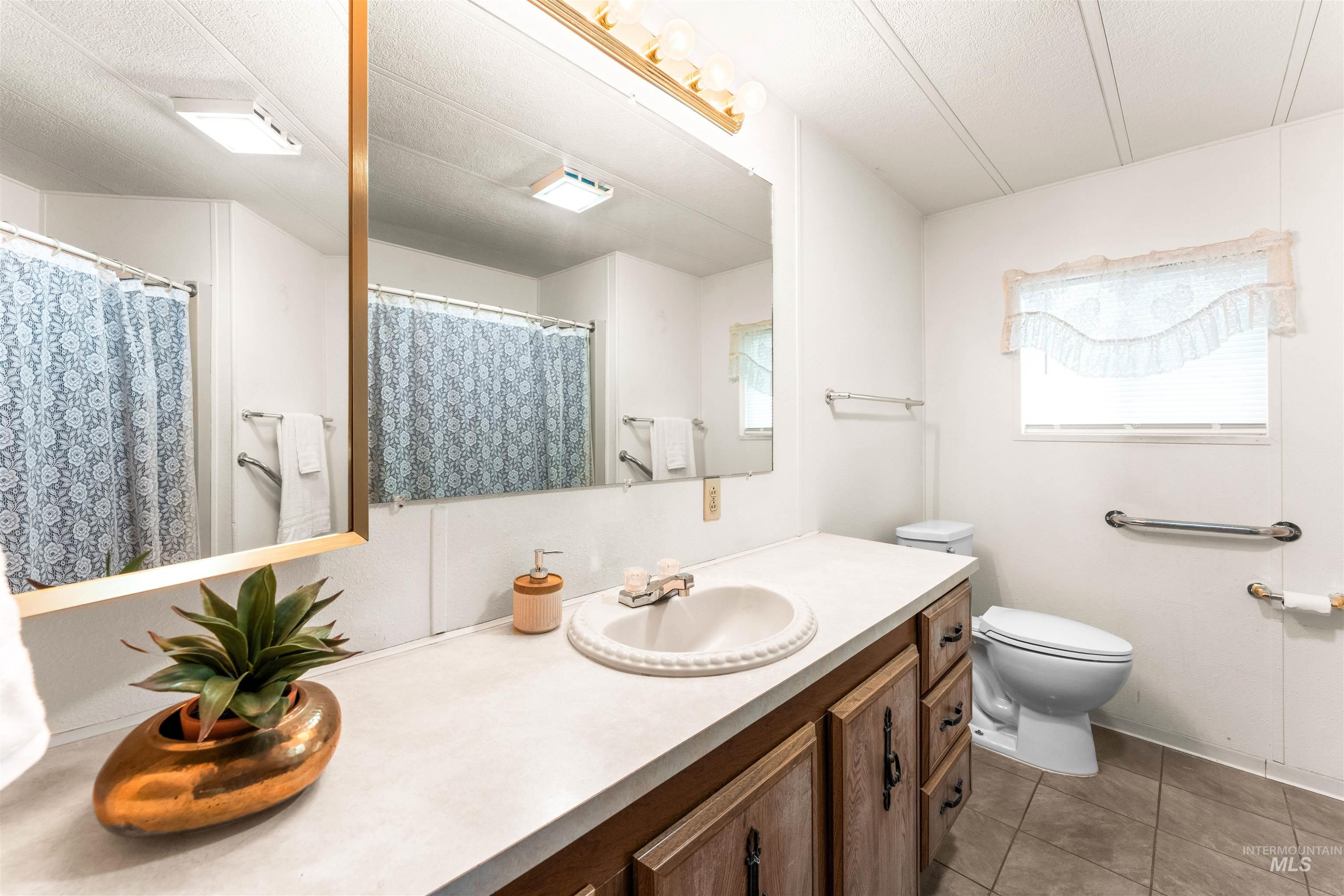 Full bath with vanity, light tile patterned floors, and a shower with curtain