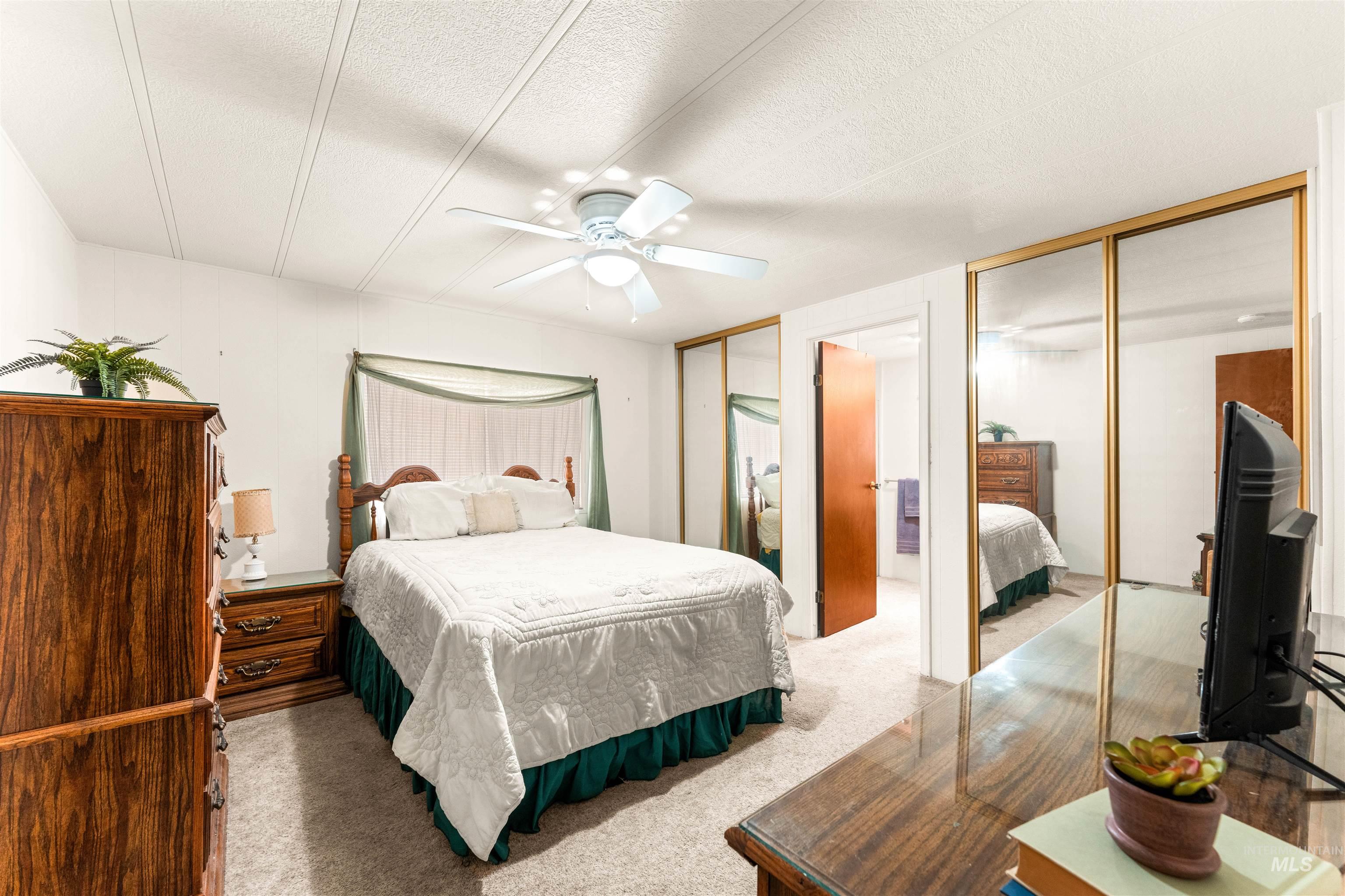 Bedroom with carpet, multiple closets, a textured ceiling, and ceiling fan
