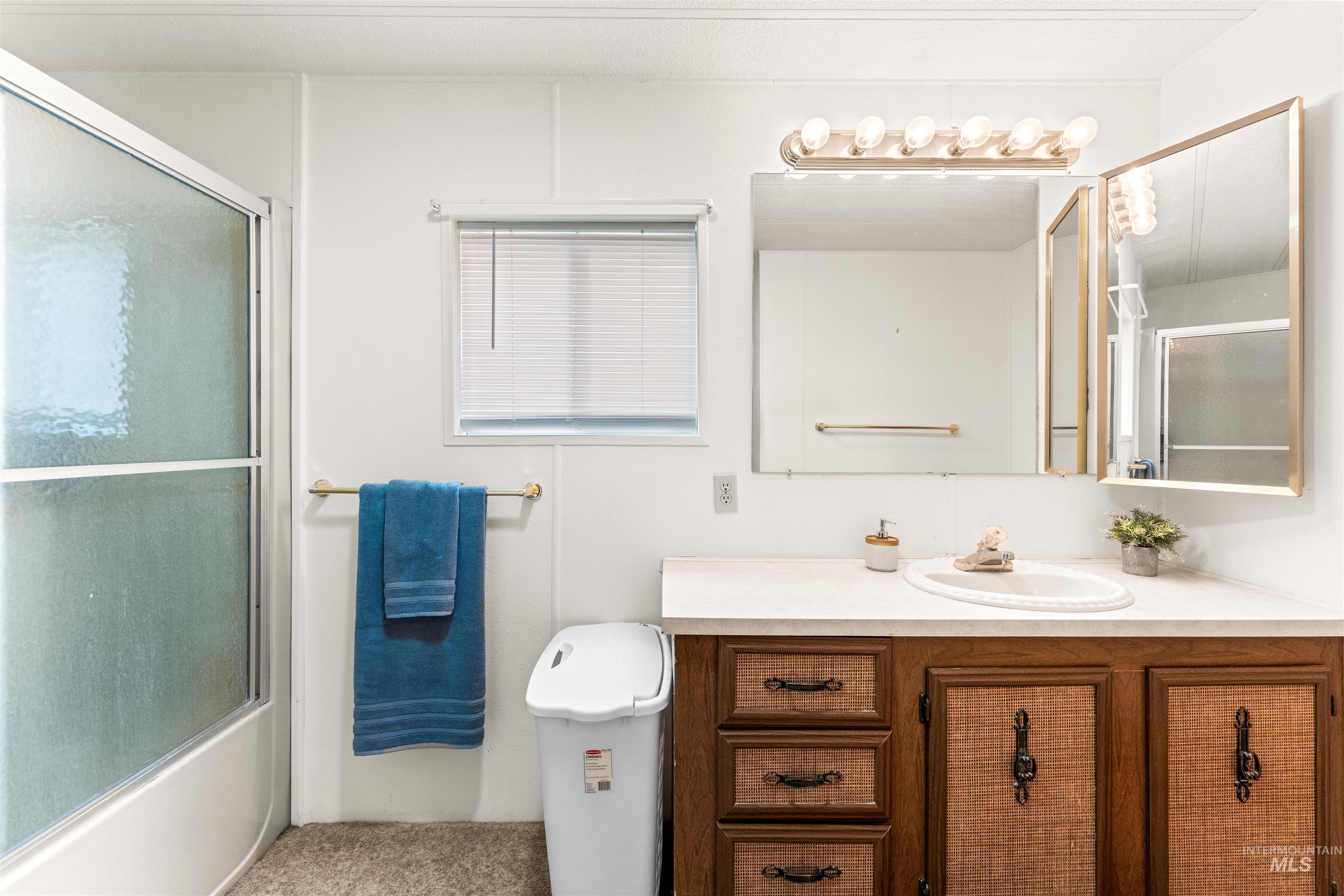 Bathroom with vanity and bath / shower combo with glass door