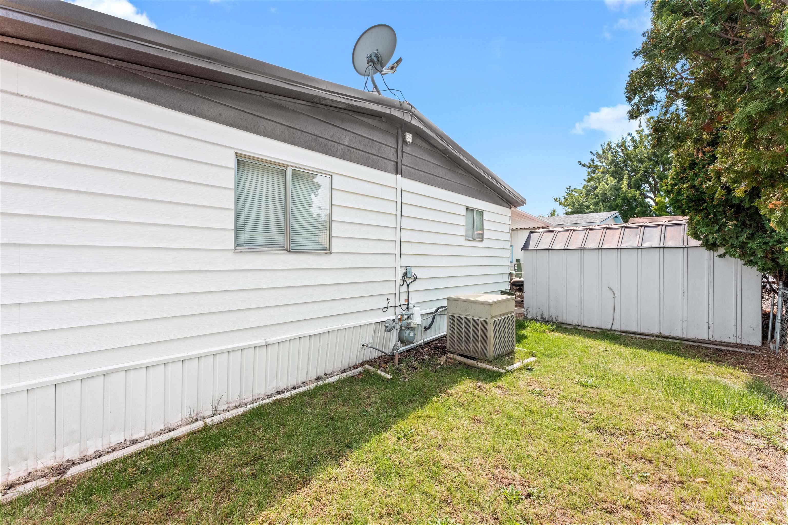 View of property exterior featuring a lawn and a storage unit