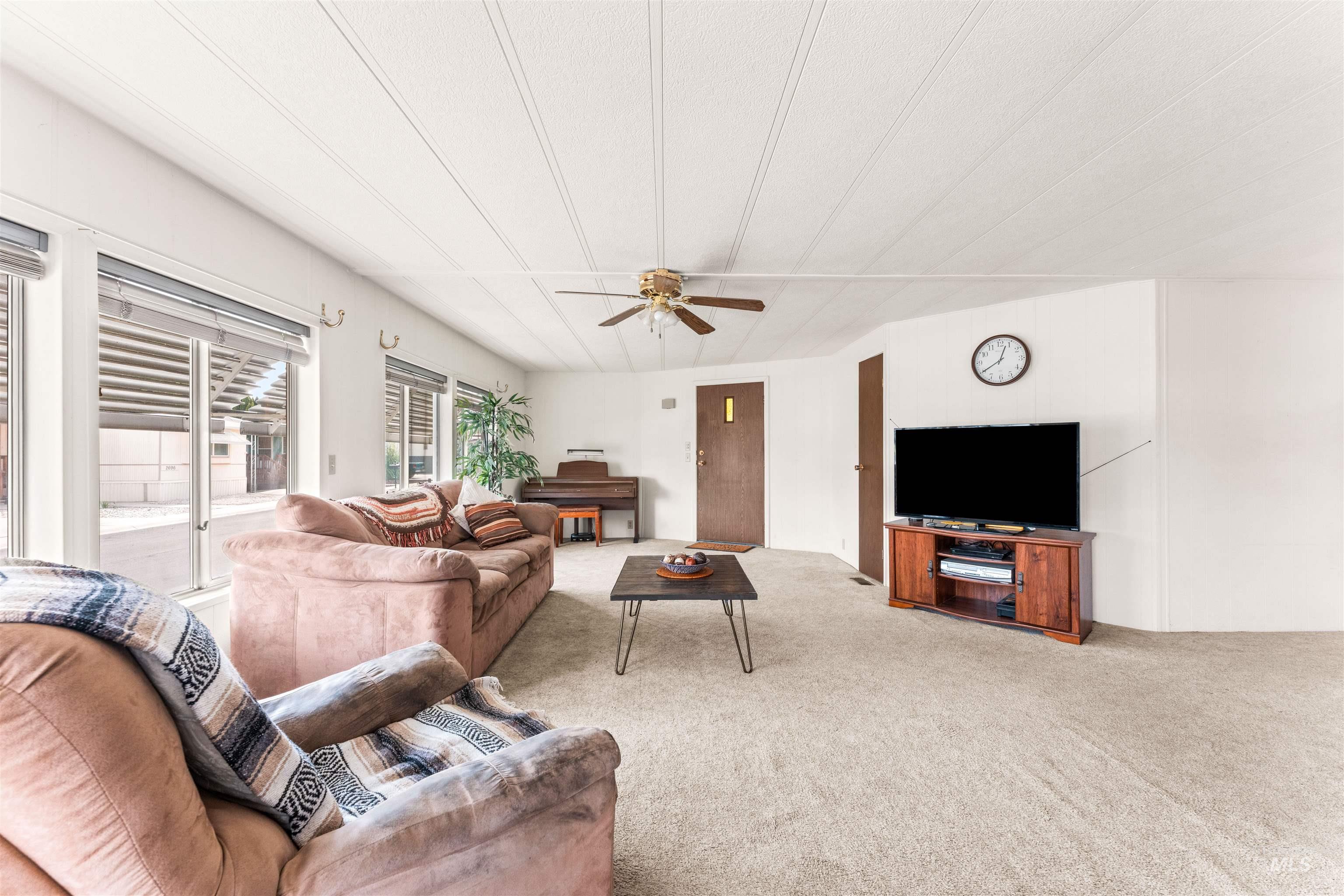 Living area with light colored carpet and ceiling fan