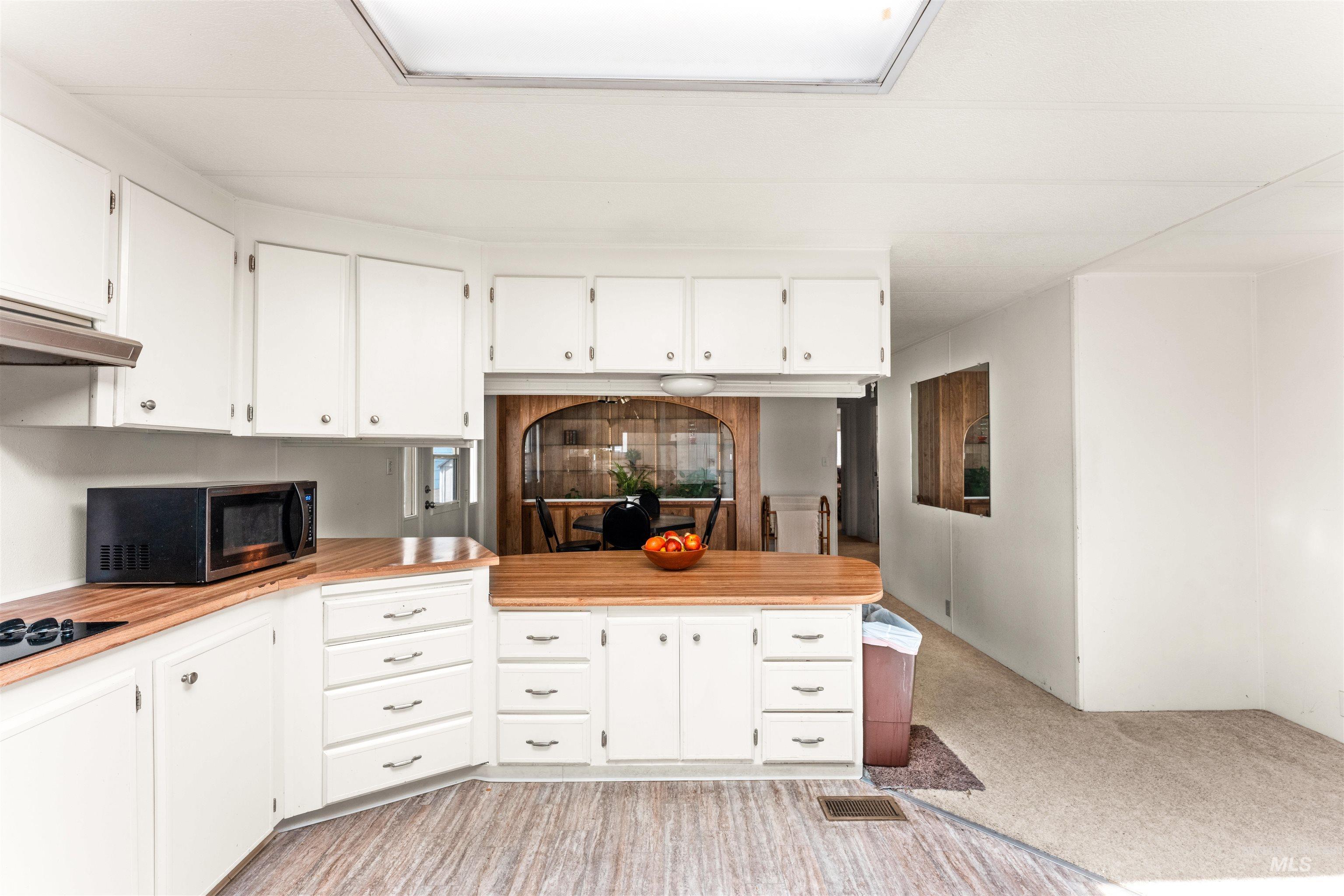 Kitchen featuring white cabinetry, a peninsula, and light carpet