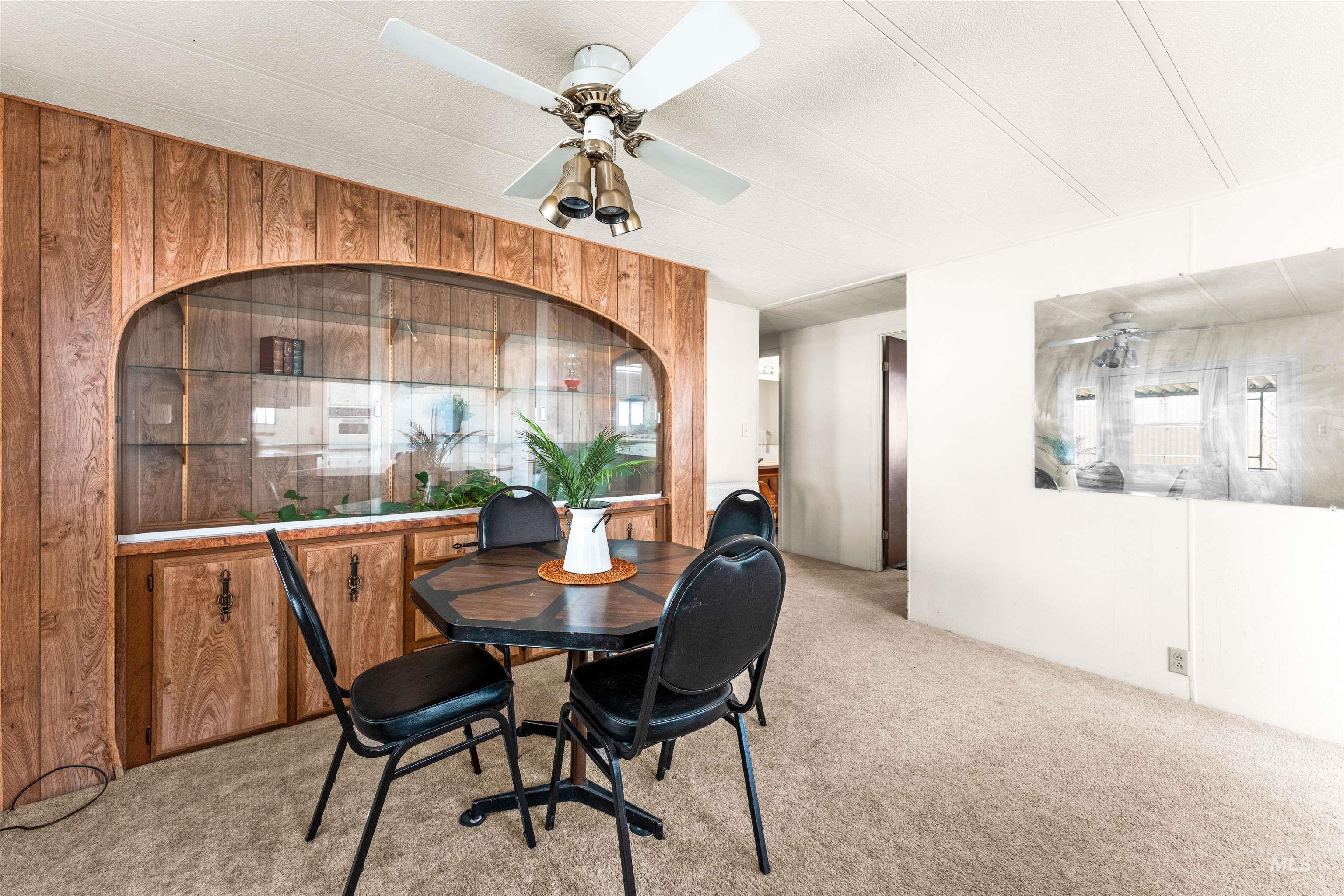 Carpeted dining space featuring wooden walls and a ceiling fan