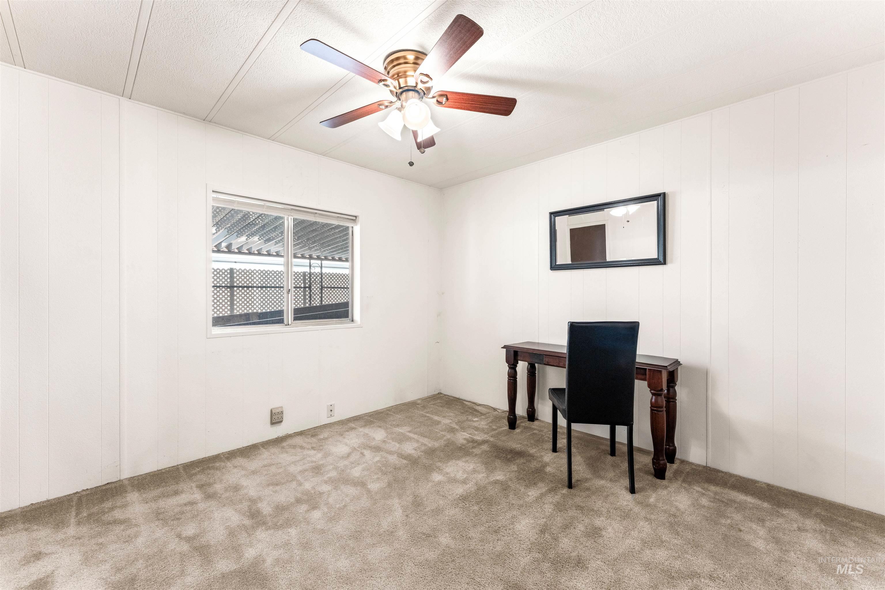 Carpeted home office with a ceiling fan