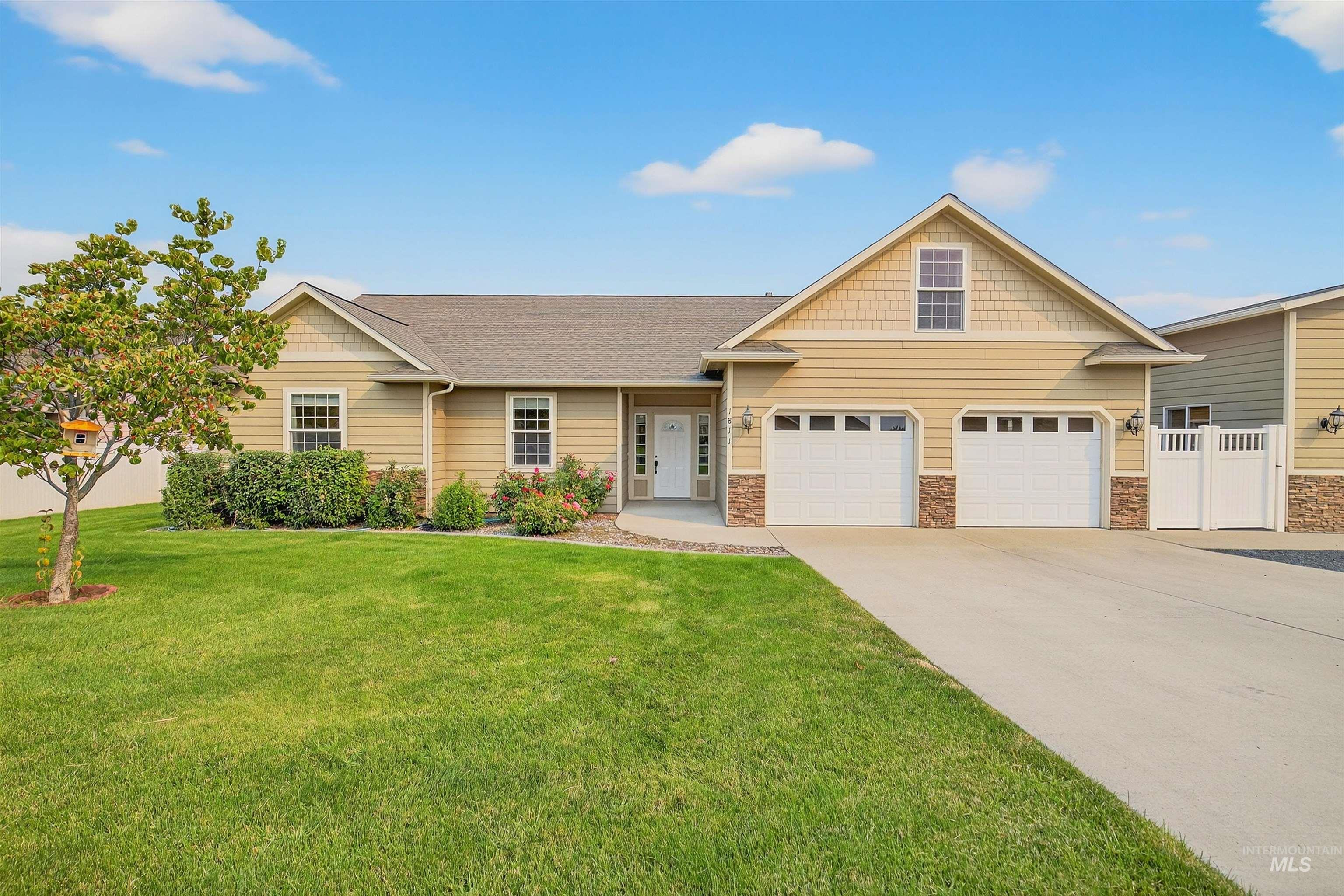 View of front of home with driveway, a front yard, a shingled roof, a garage, and stone siding