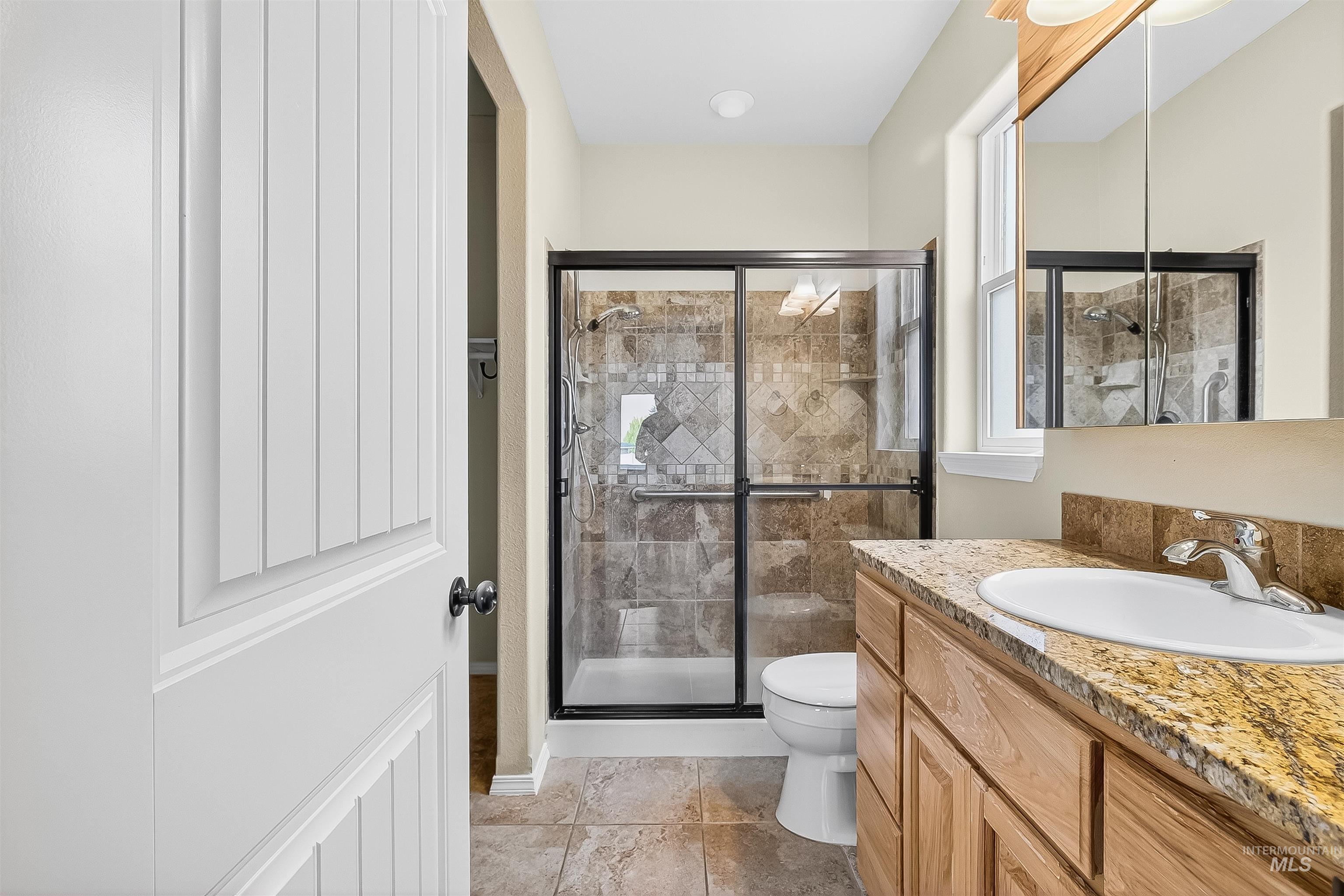Bathroom featuring vanity, a stall shower, and light tile patterned floors