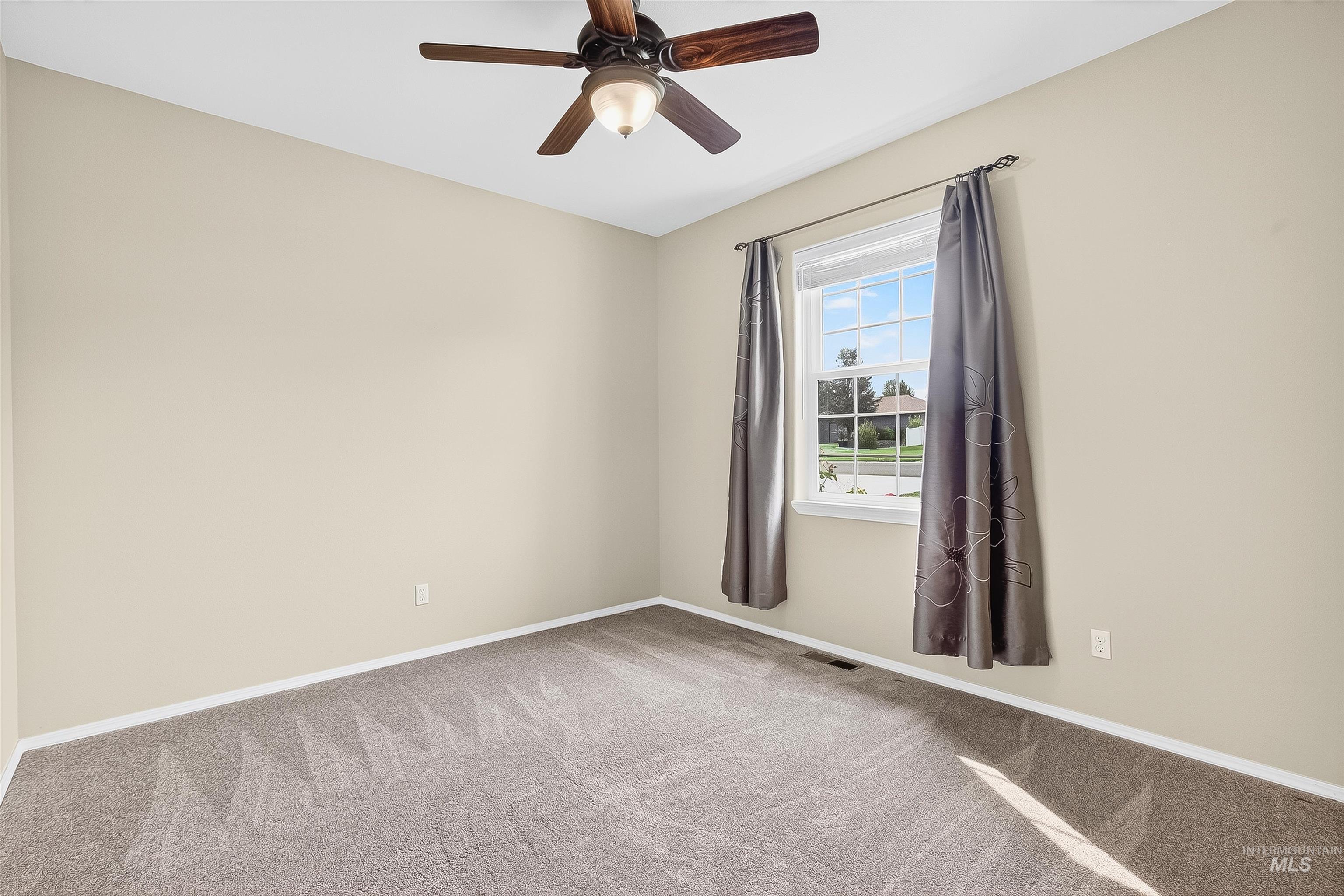 Carpeted empty room with baseboards and a ceiling fan