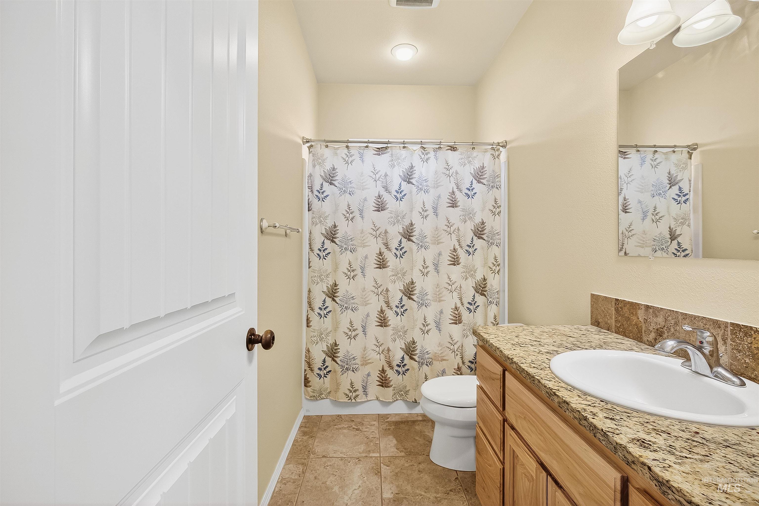 Full bath with vanity, a shower with shower curtain, and light tile patterned floors