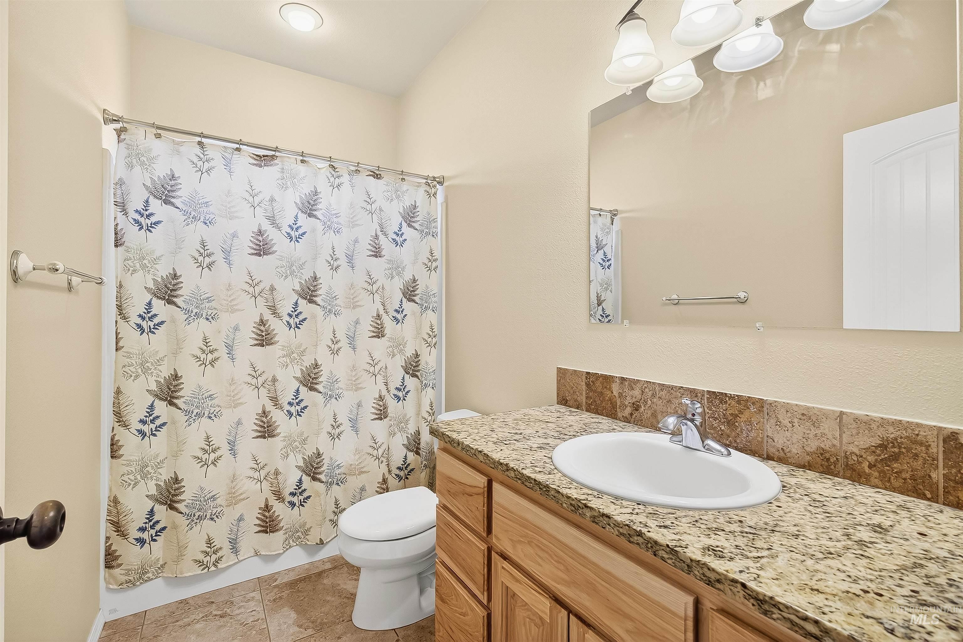 Bathroom featuring vanity, light tile patterned flooring, and curtained shower