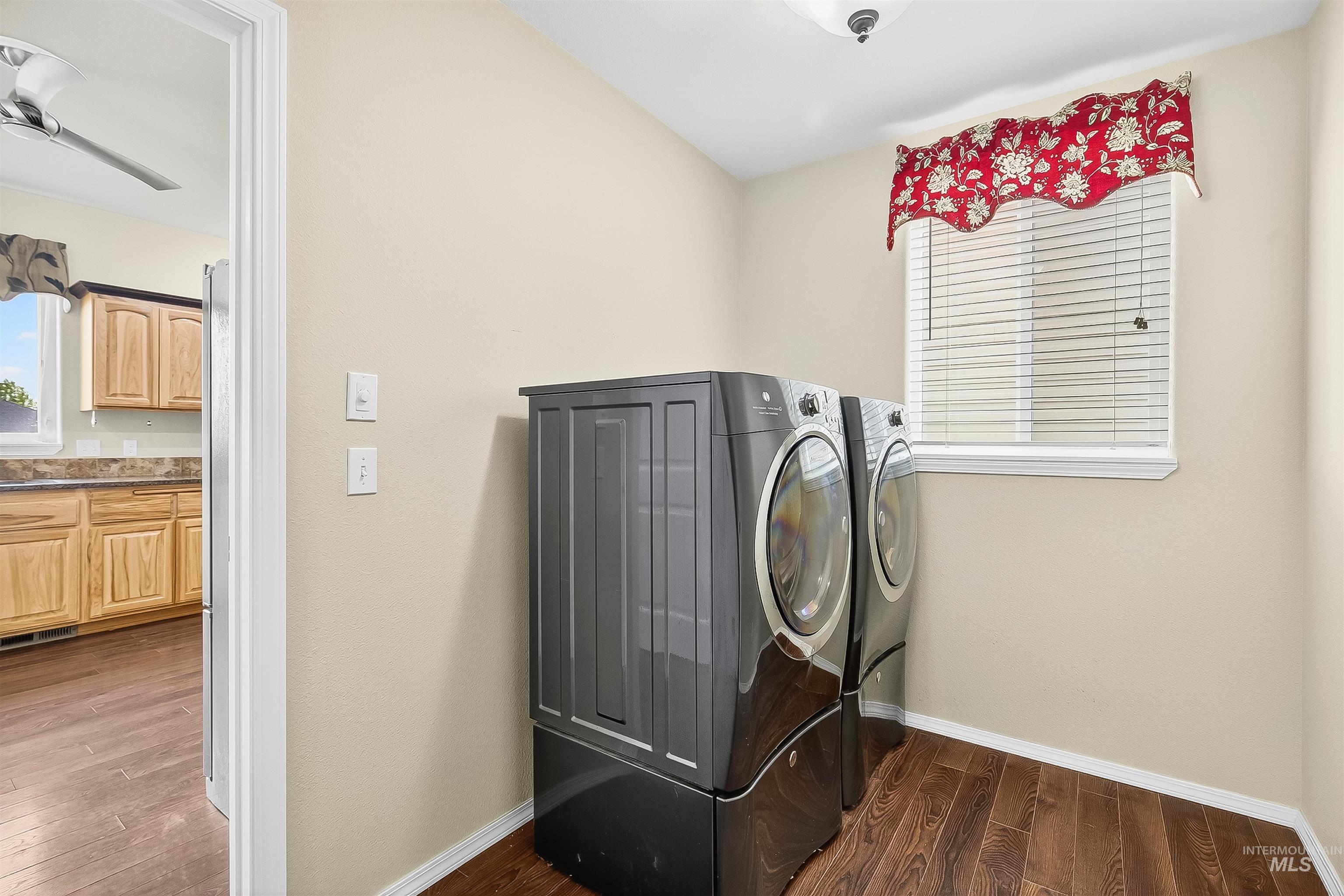 Laundry room featuring dark wood-style floors, washing machine and clothes dryer, and a ceiling fan