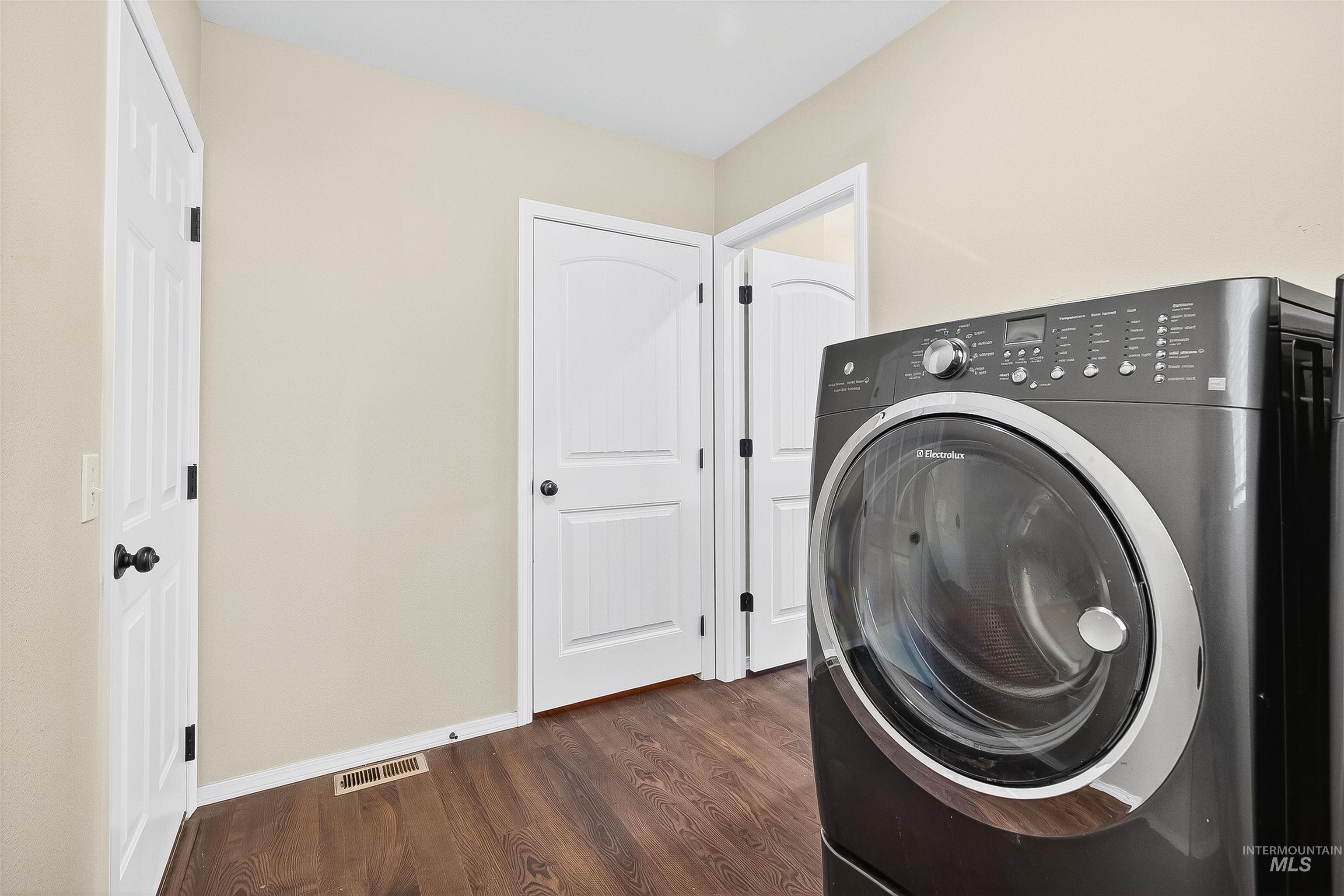 Washroom featuring washer / dryer and dark wood finished floors