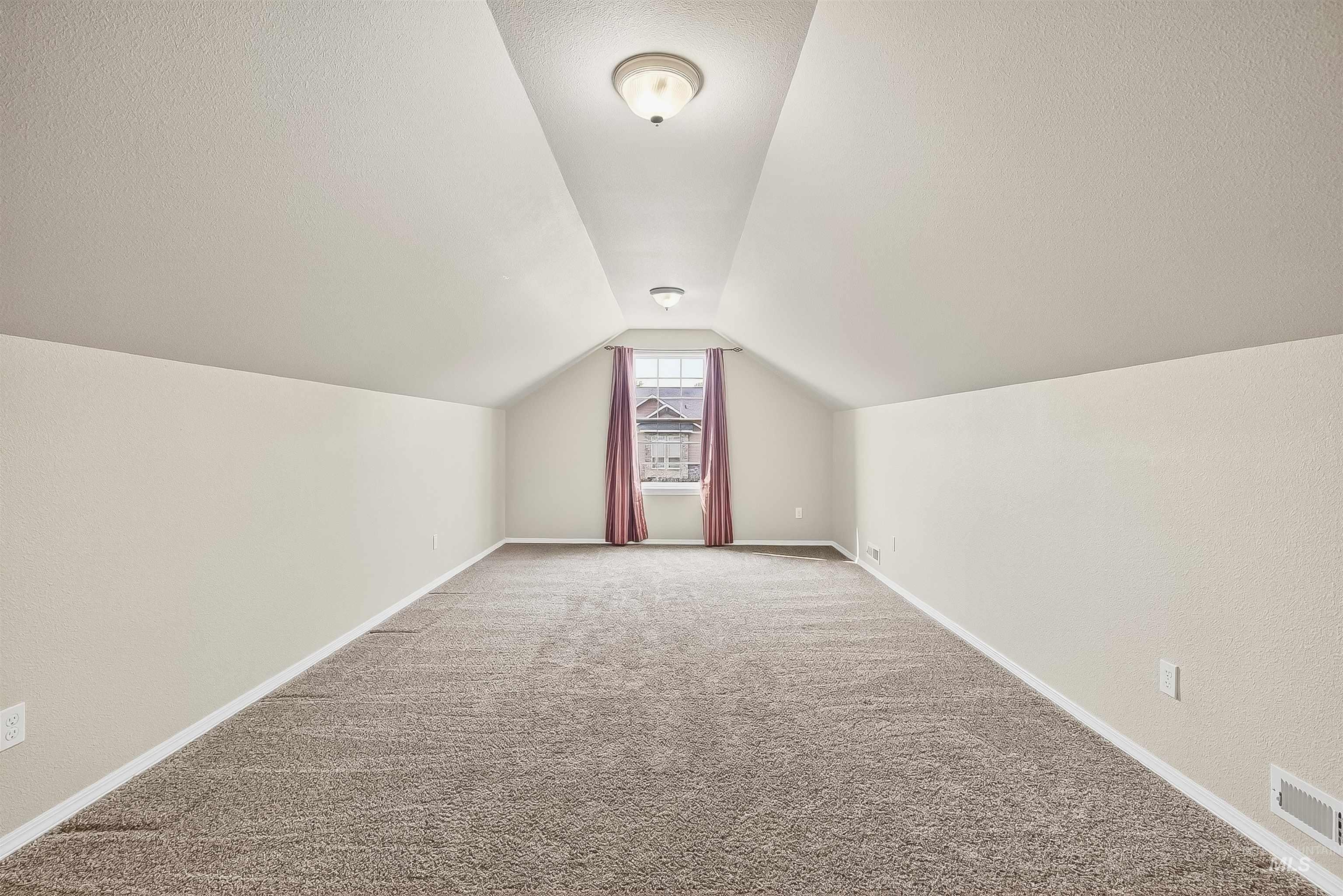 Bonus room featuring carpet flooring, vaulted ceiling, and a textured ceiling