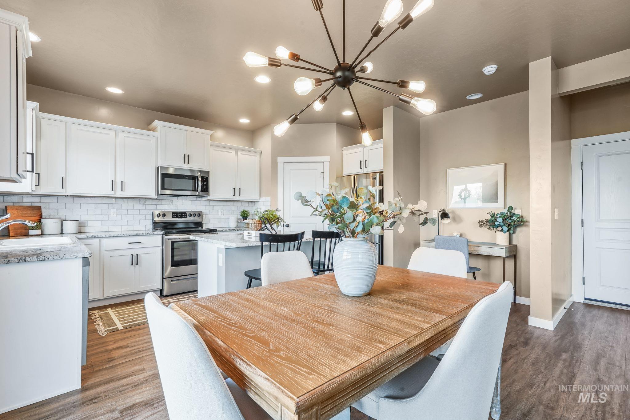 Dining area featuring dark wood-style floors, recessed lighting, and a chandelier
