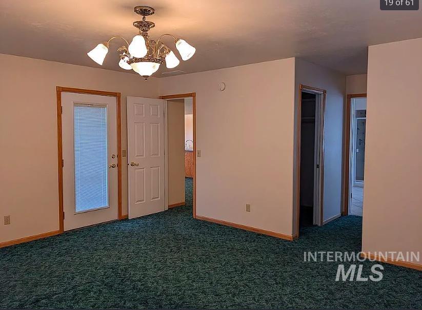 Spare room with a chandelier and dark colored carpet