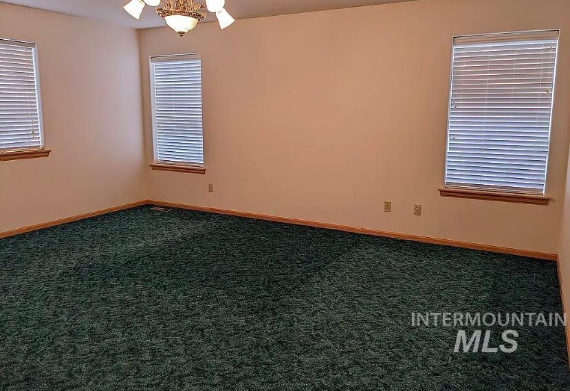 Empty room featuring dark carpet and baseboards