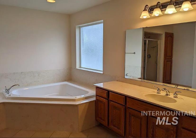 Bathroom with a shower stall, vanity, a bath, and light tile patterned flooring