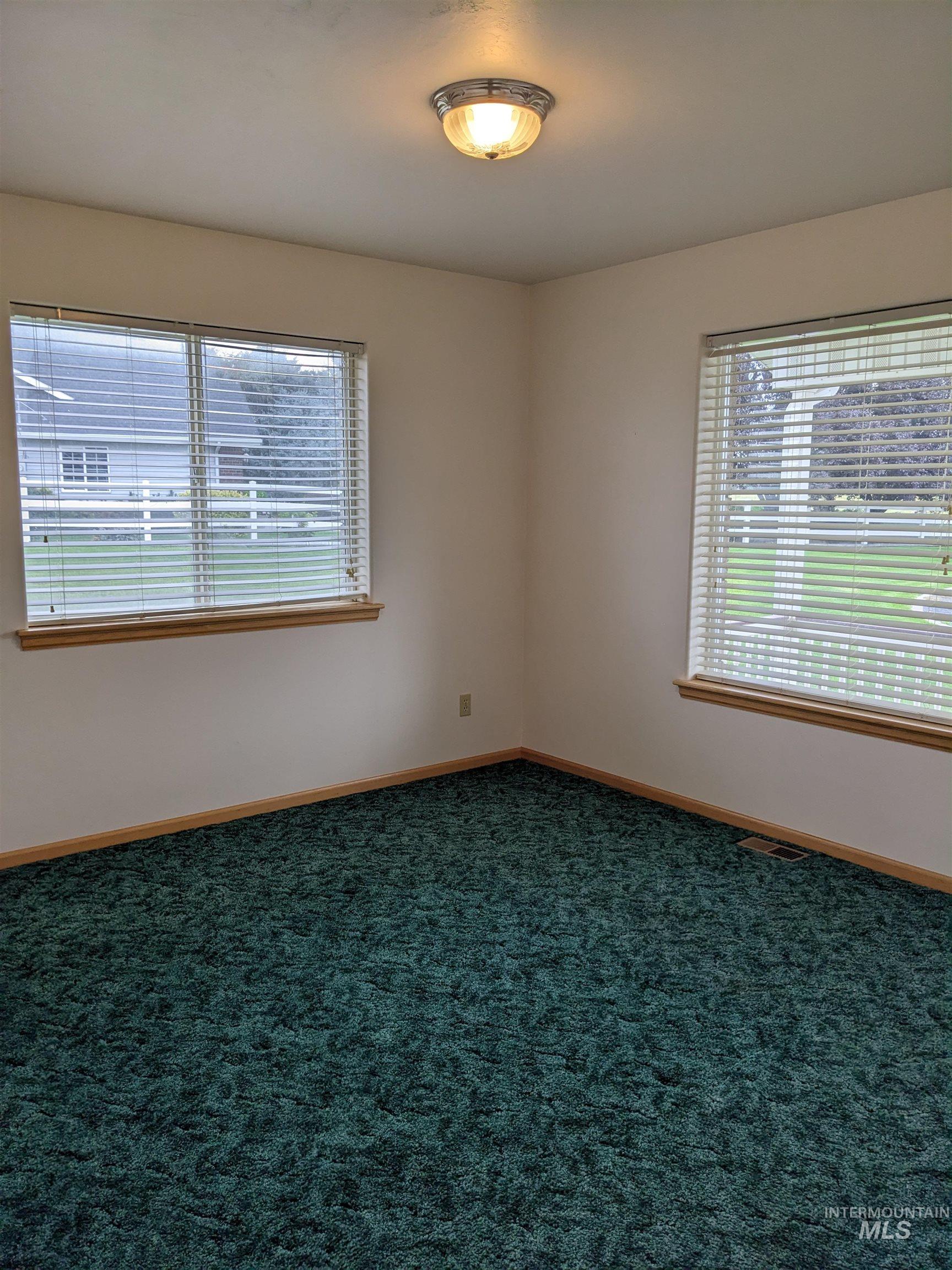Unfurnished room featuring baseboards and dark colored carpet