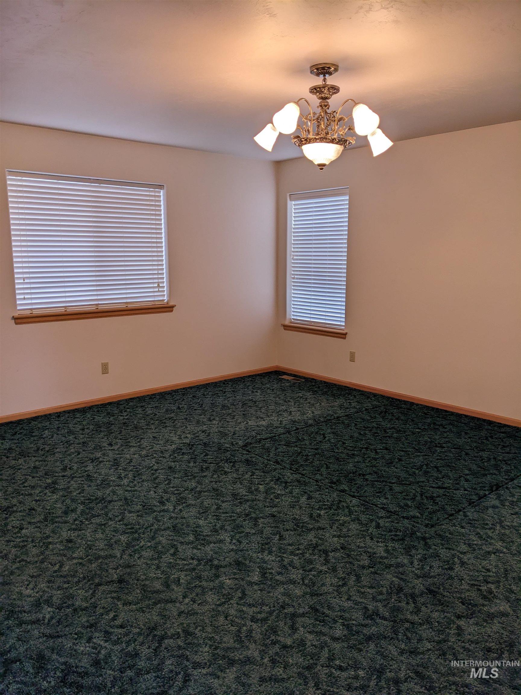 Carpeted spare room with baseboards and a chandelier