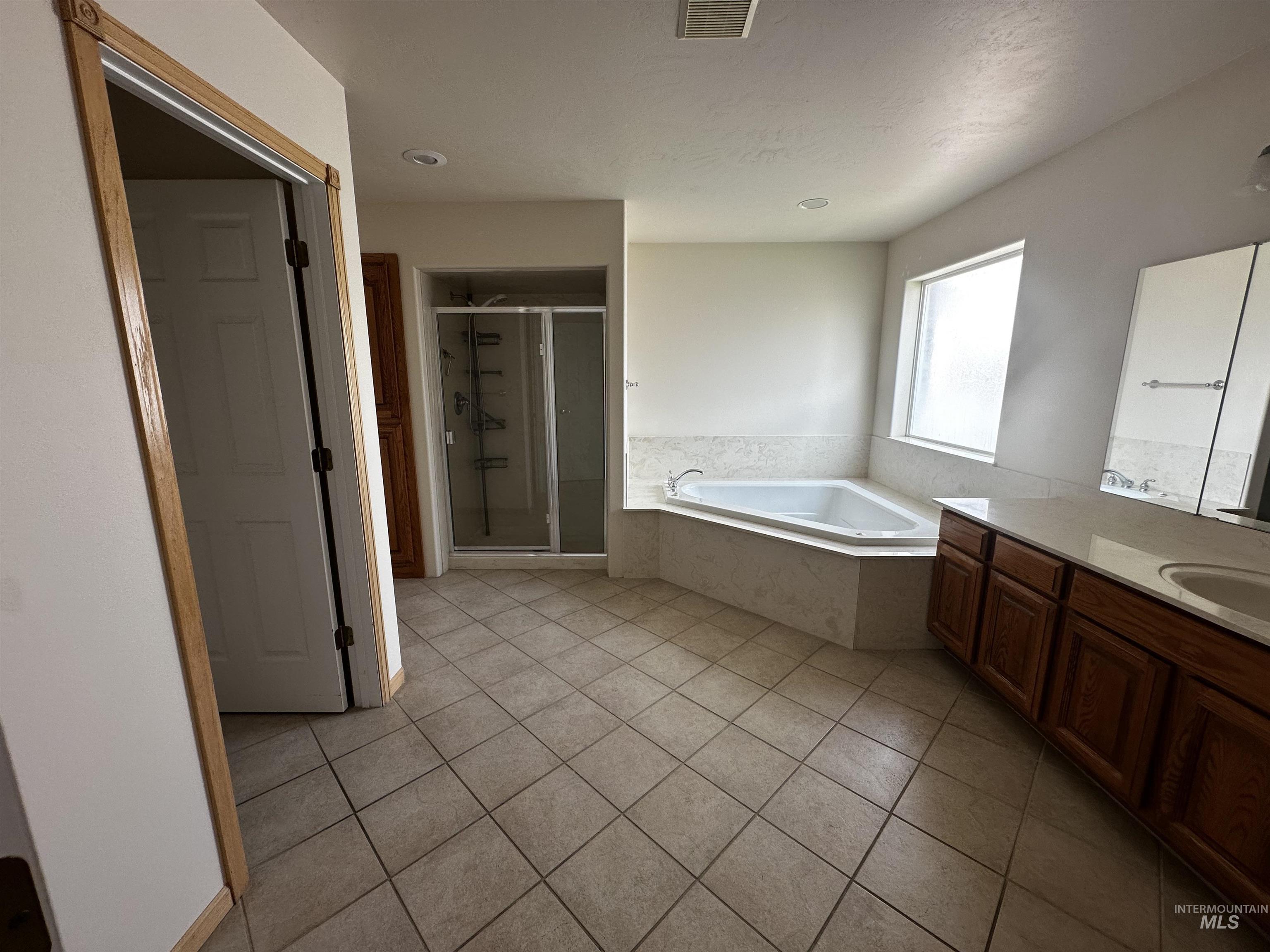 Bathroom with vanity, a shower stall, a bath, and light tile patterned floors