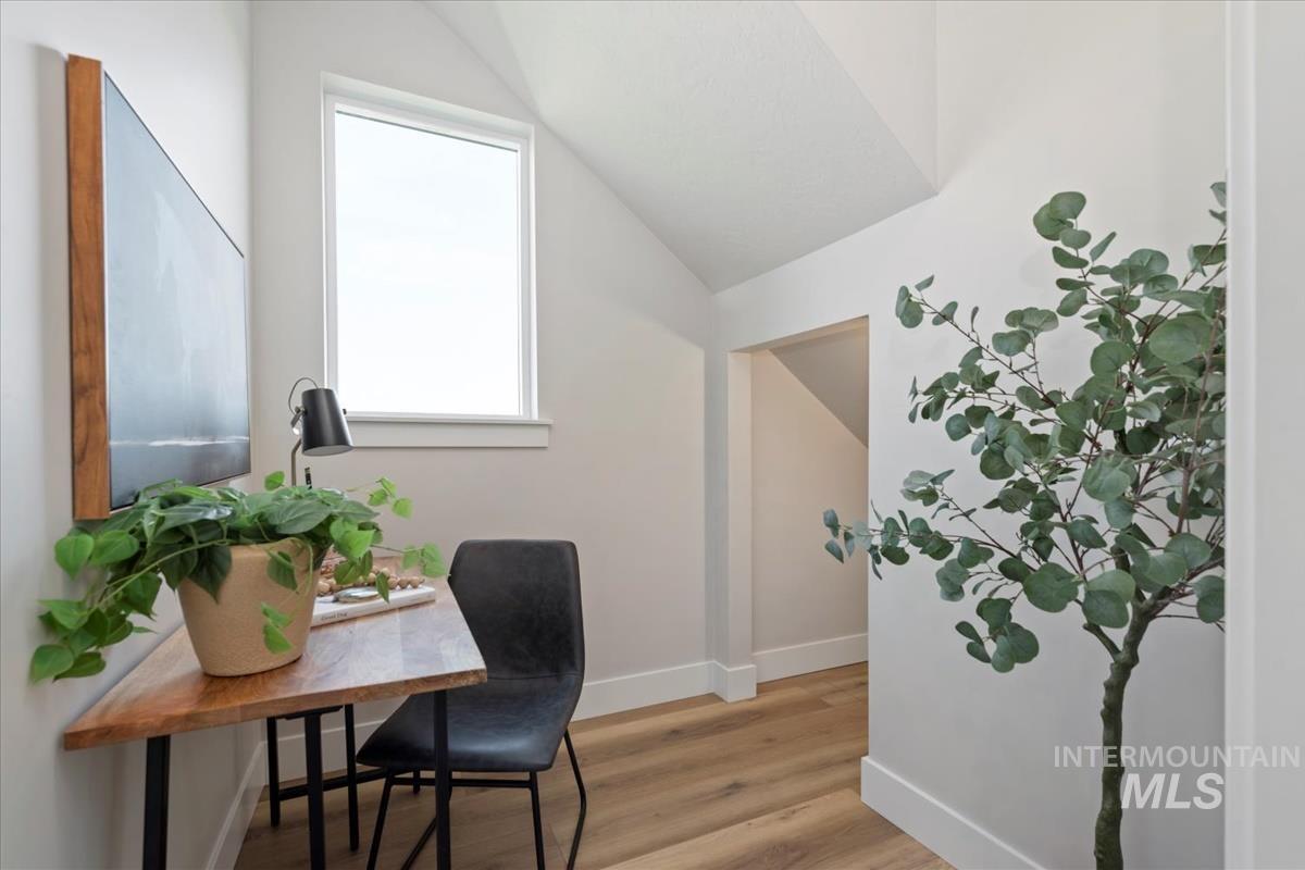 Office area featuring light wood-style flooring and vaulted ceiling