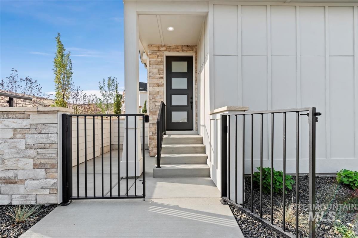 Property entrance with a gate, board and batten siding, and stone siding