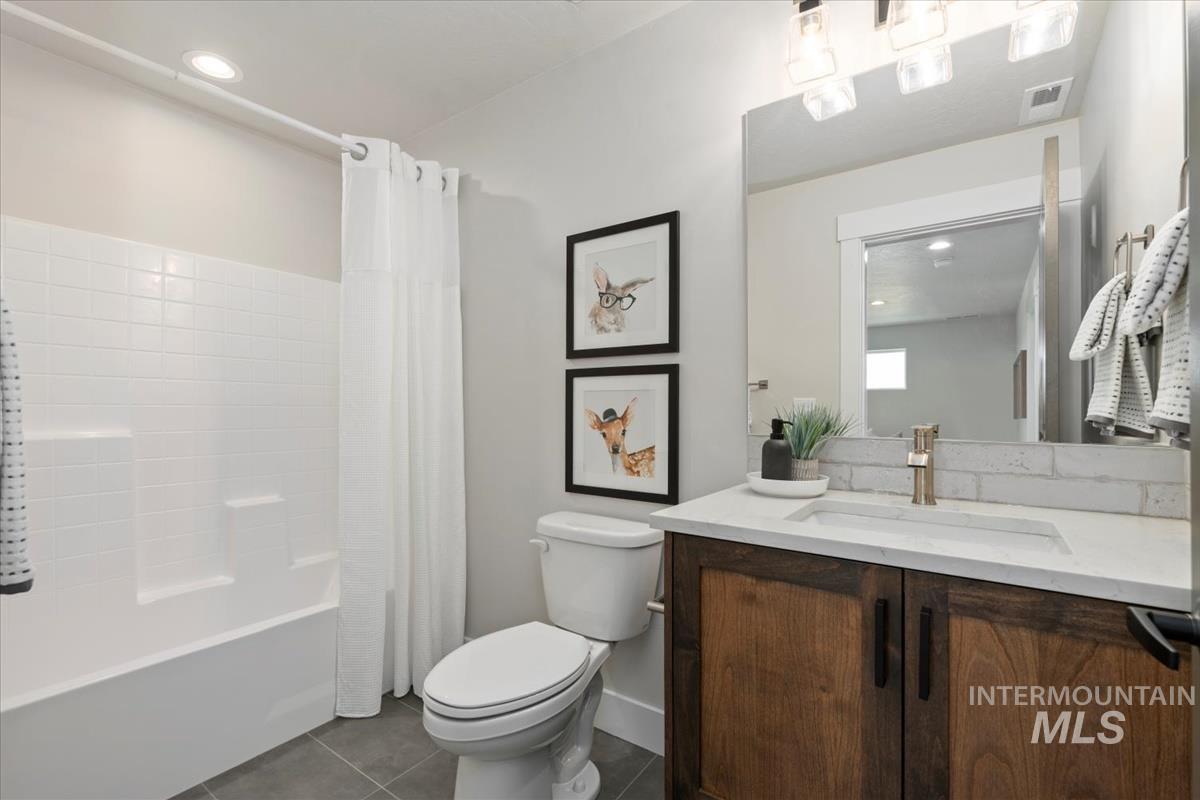 Full bath with dark tile patterned flooring, shower / bathtub combination with curtain, vanity, and recessed lighting