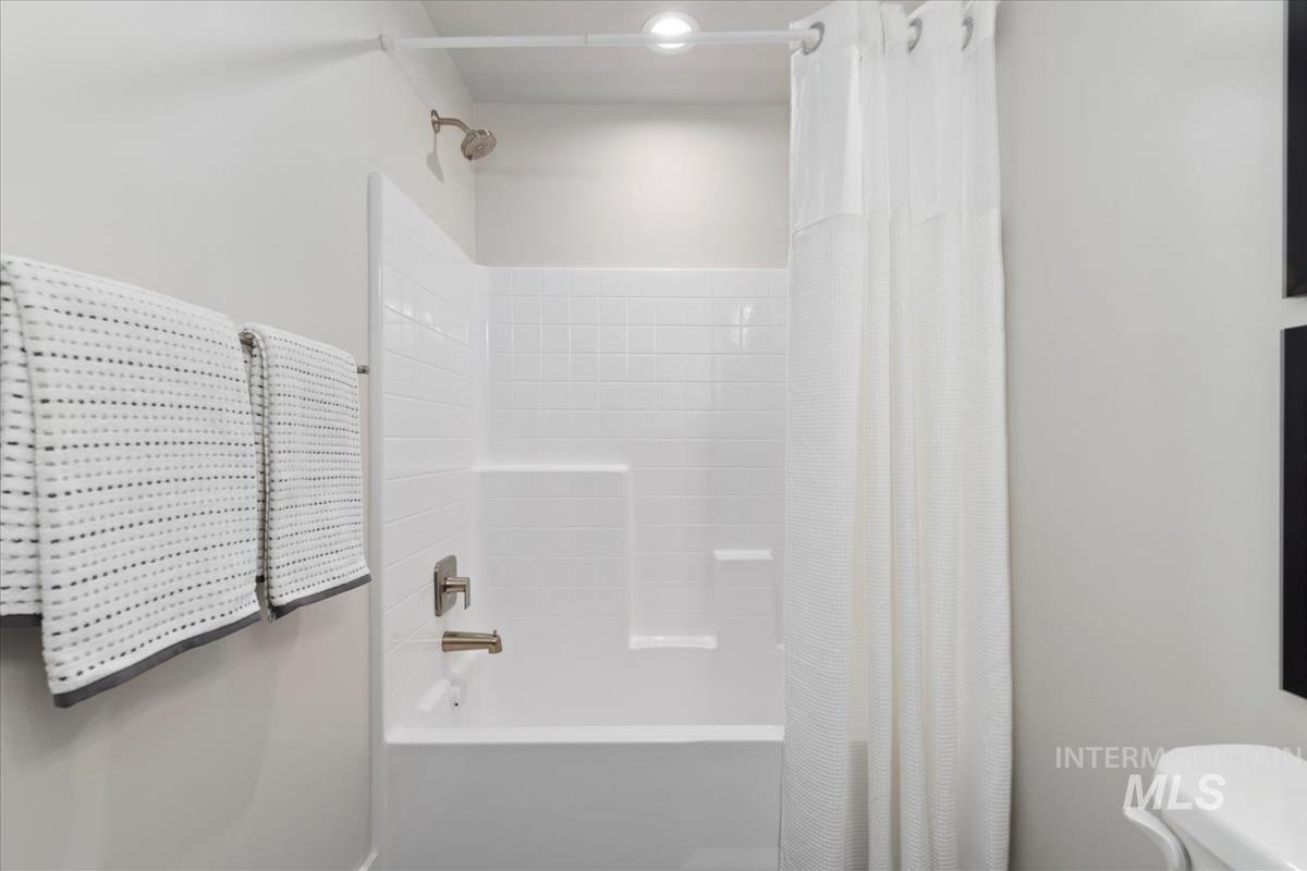 Bathroom with shower / bathtub combination with curtain and toilet