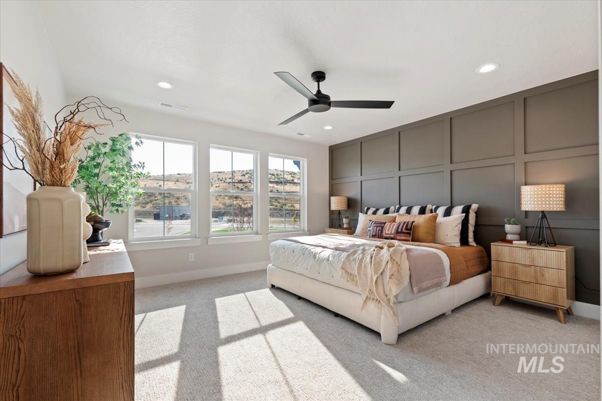 Bedroom featuring a decorative wall, light colored carpet, ceiling fan, and recessed lighting