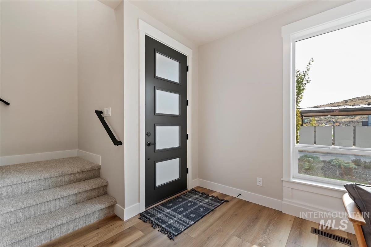 Entrance foyer with healthy amount of natural light, light wood-style flooring, and stairs