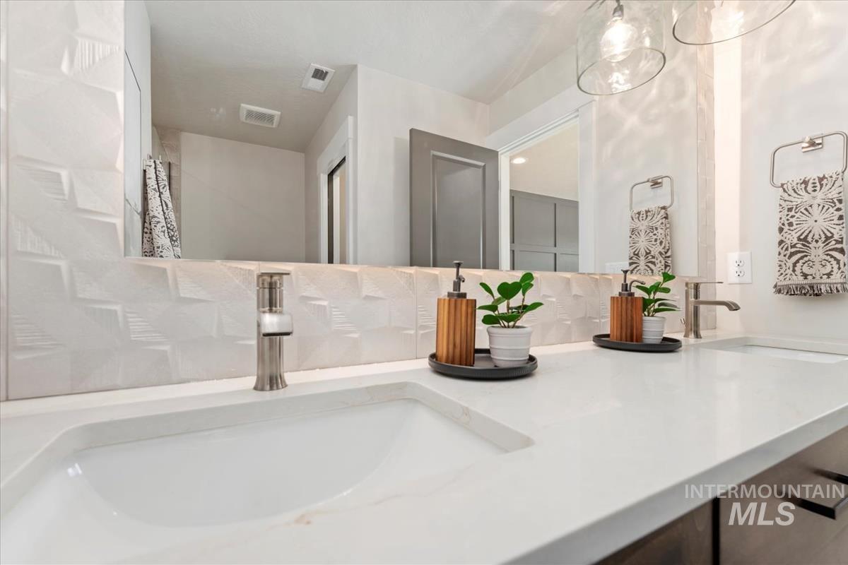 Bathroom featuring double vanity and tasteful backsplash