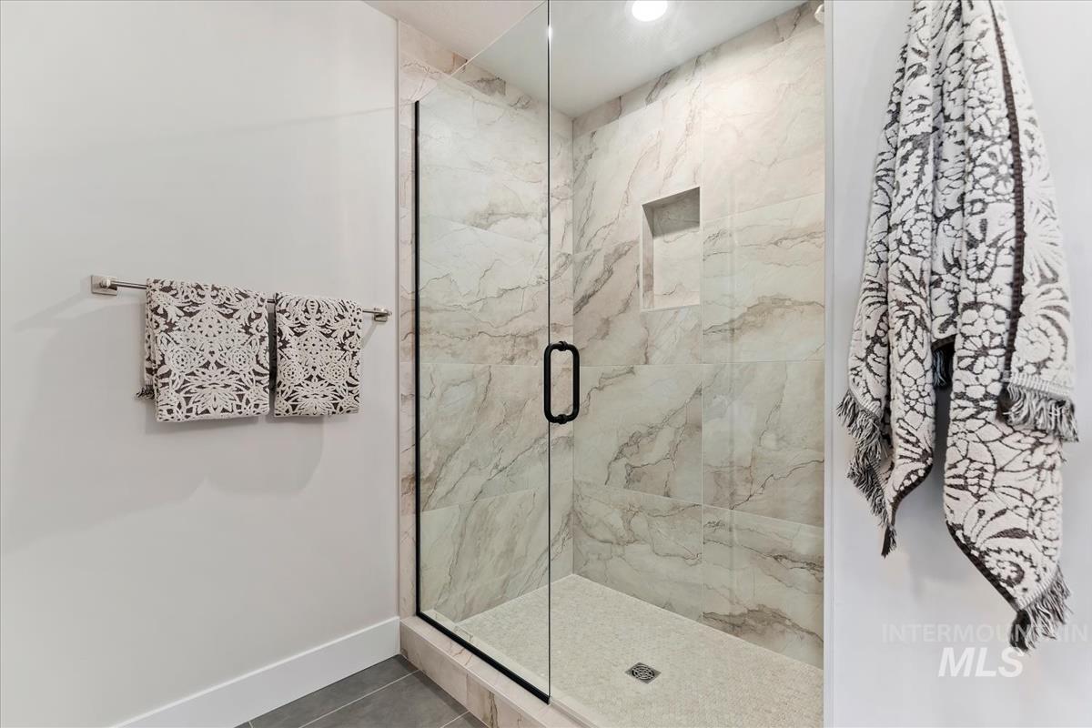 Bathroom with a marble finish shower and tile patterned flooring